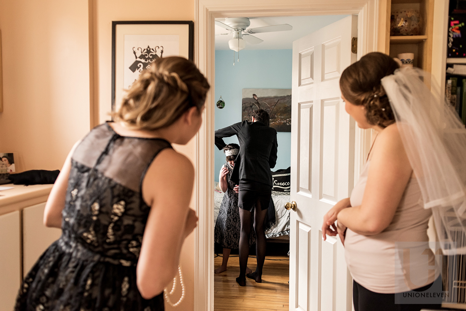 The bride and her Maid of Honour looking over to their bridesmaid getting the final touches of her dress