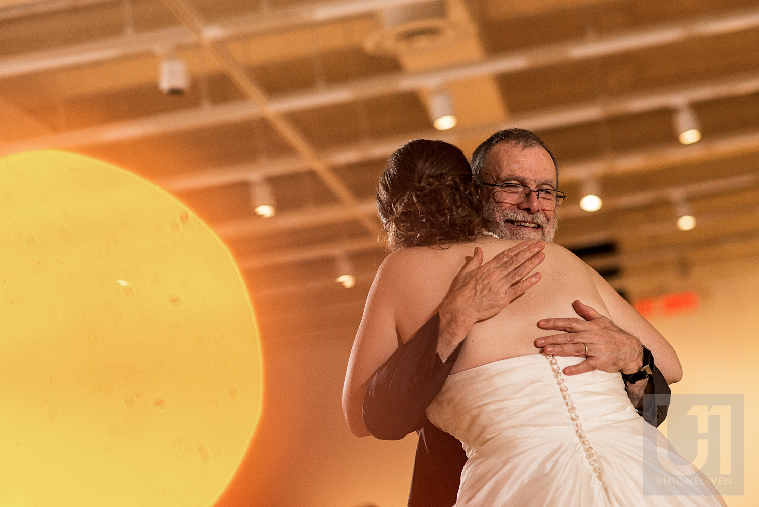 A photo of a hug between the bride and her father at the wedding reception