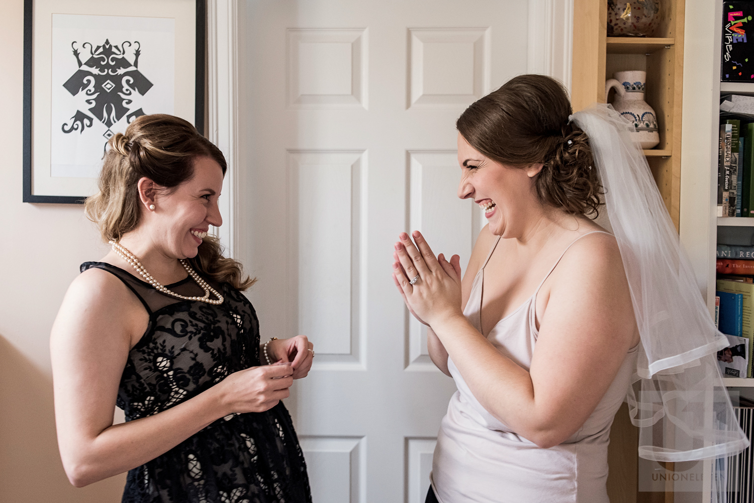 The bride and her bridesmaid sharing a laugh while they get ready