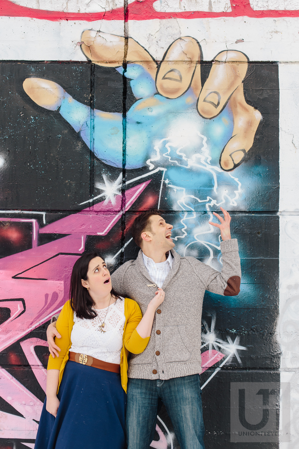 Engagement shoot of the couple doing a dramatic pose in front of a graffiti wall in Ottawa