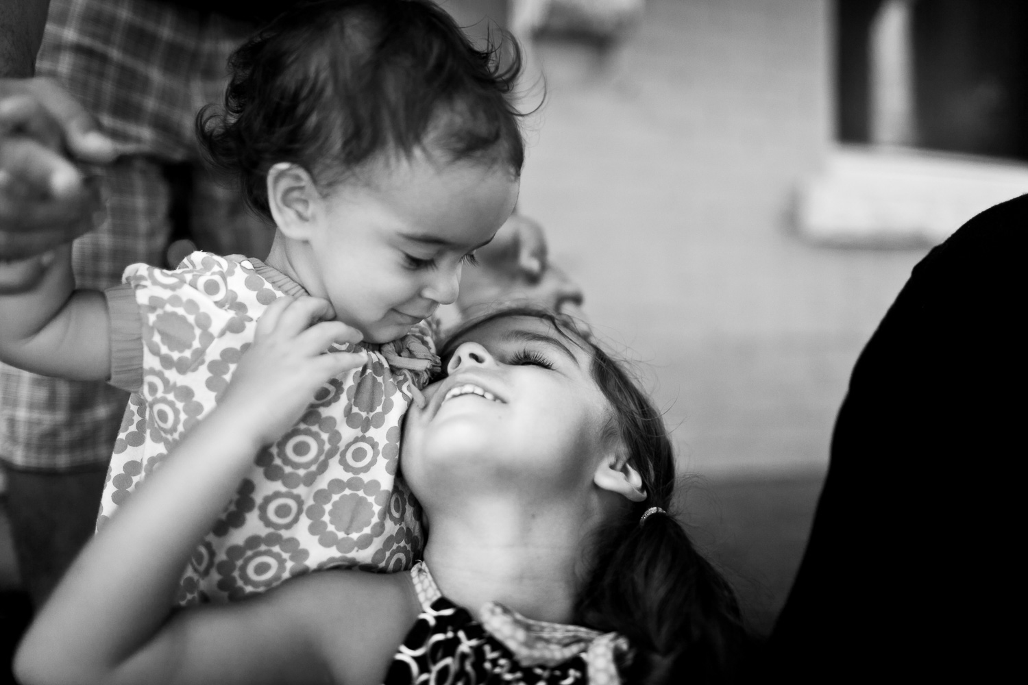 candid black and white photograph of two young sisters with their dad in the background (Copy)