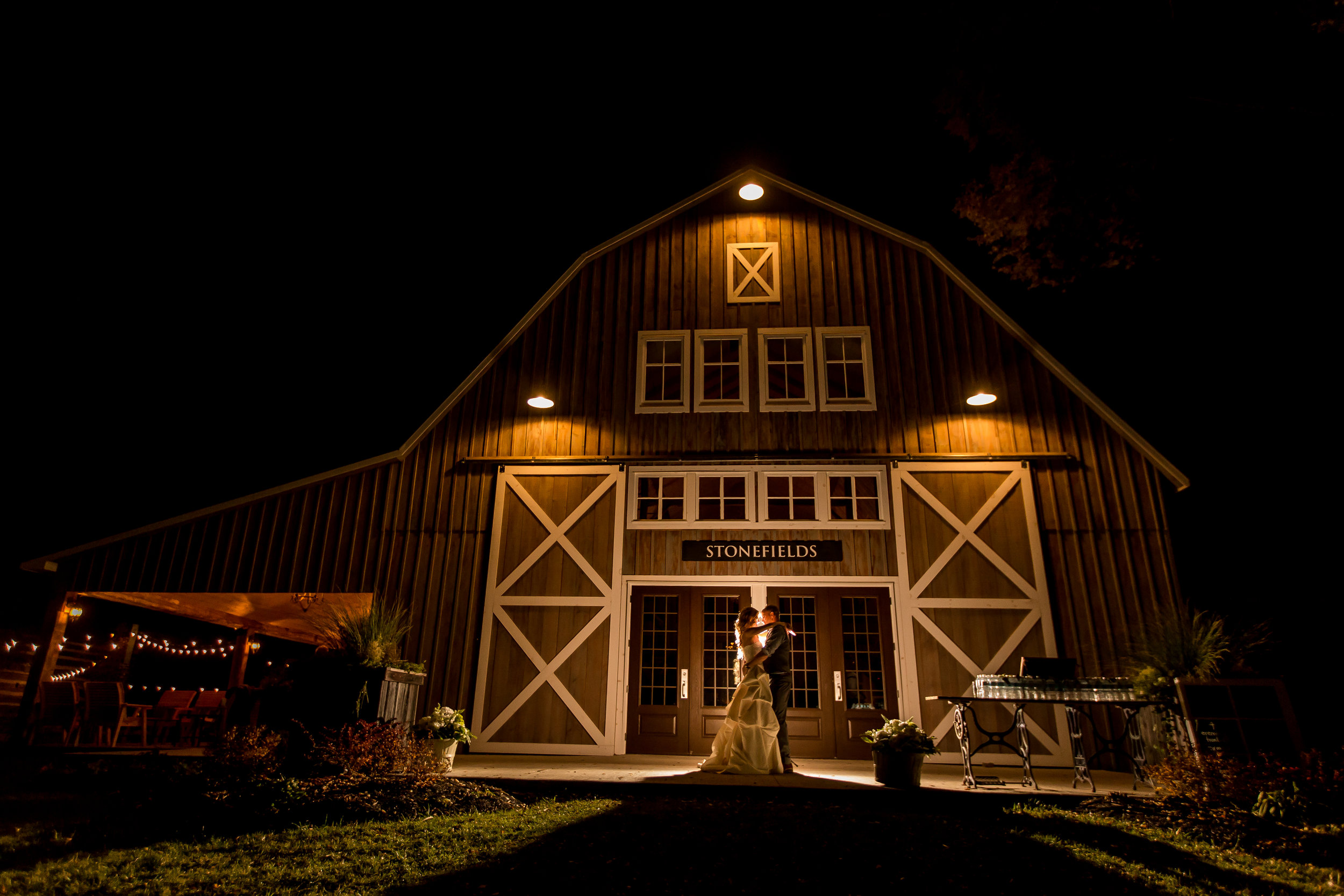 A nighttime portrait of the bride and groom outside the new Stonefields barn