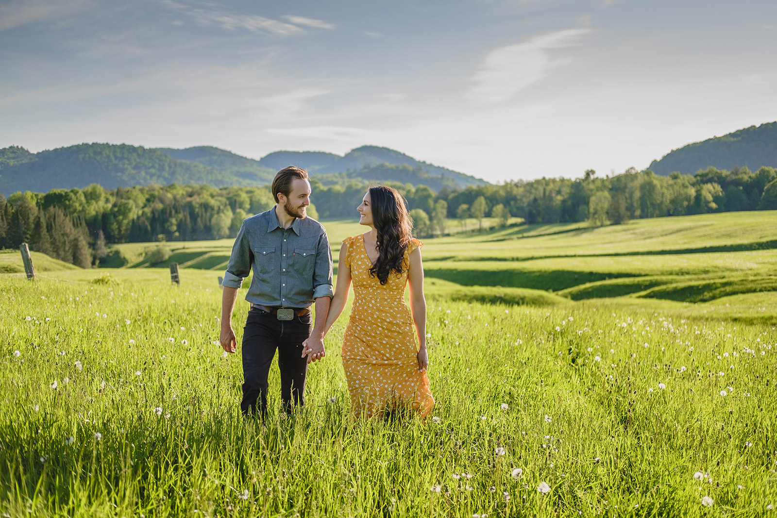 country couple pose for enagement photo in a beautiful farm field