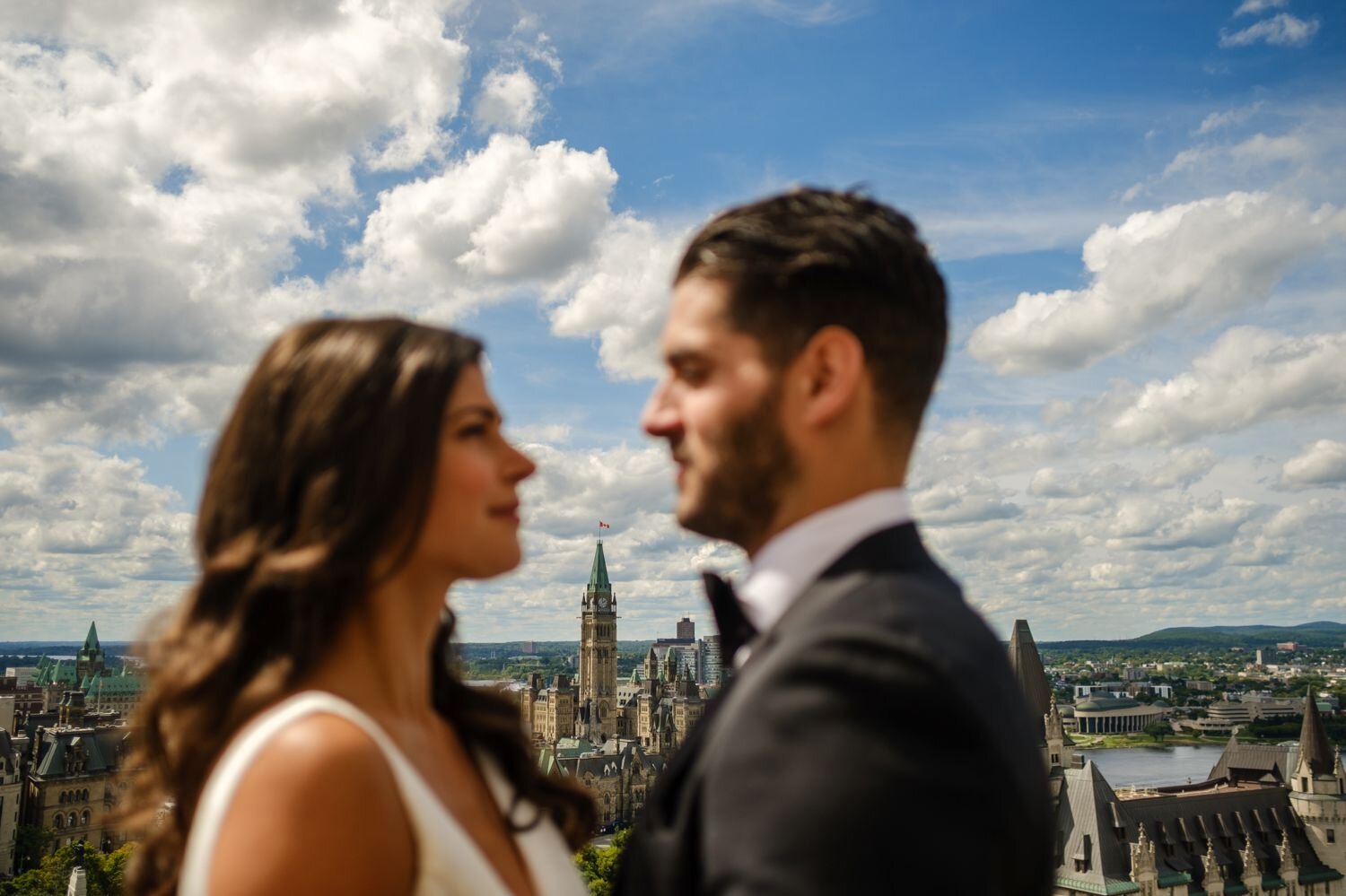 bride and groom pose for photo on the roottop of the westin hotel with ottawa in the background