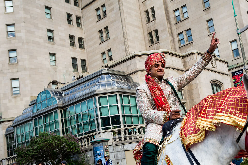 Indian groom riding on a horse in front of Ottawa's Chateau Laurier