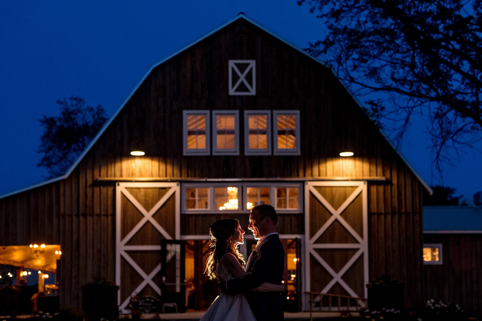 Portrait of a bride and groom taken at dusk in front of a barn at Stonefields