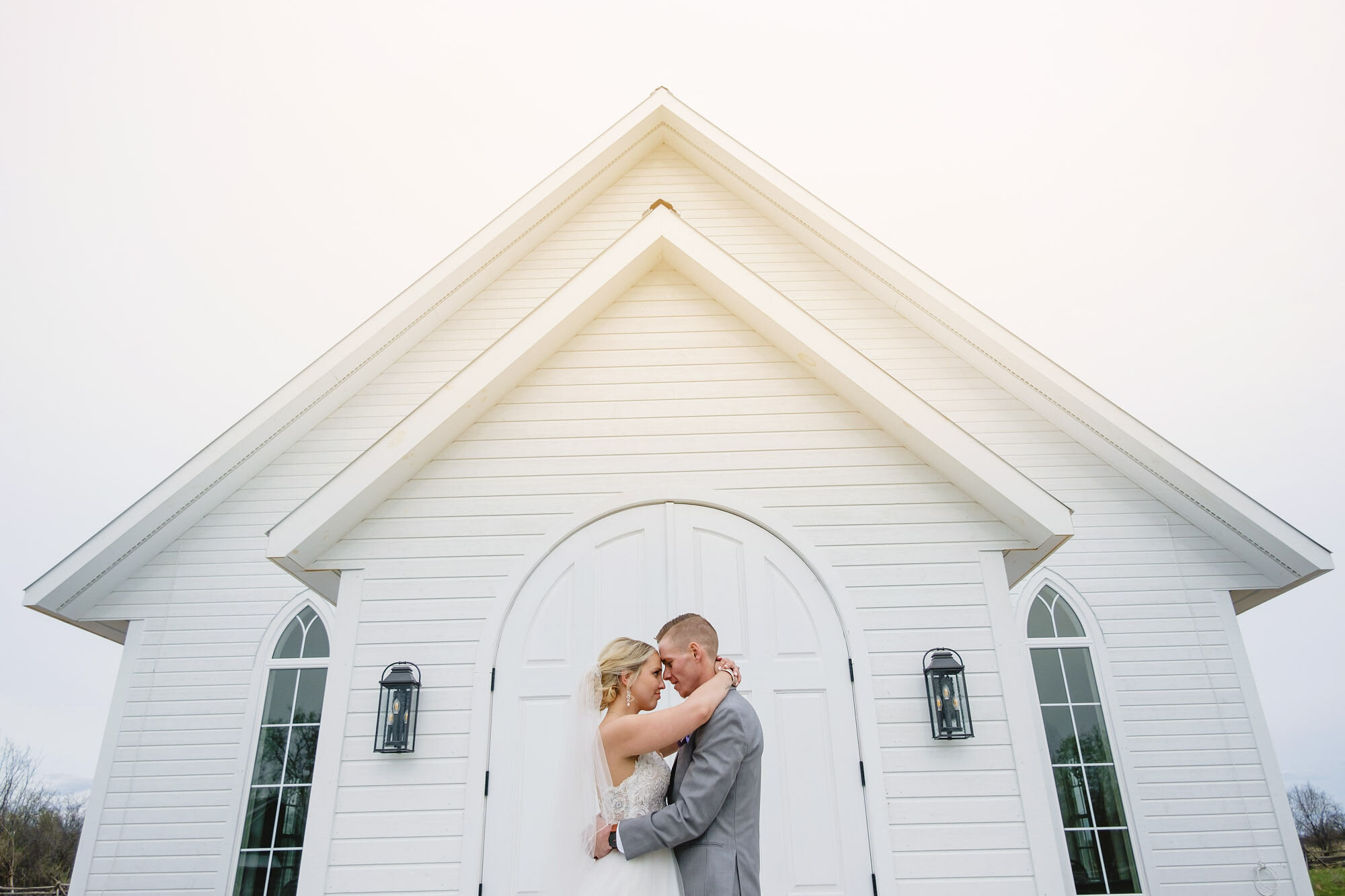 Bride and groom holding each other and touching foreheads in front of Ceremony House at Stonefields Estate near Ottawa