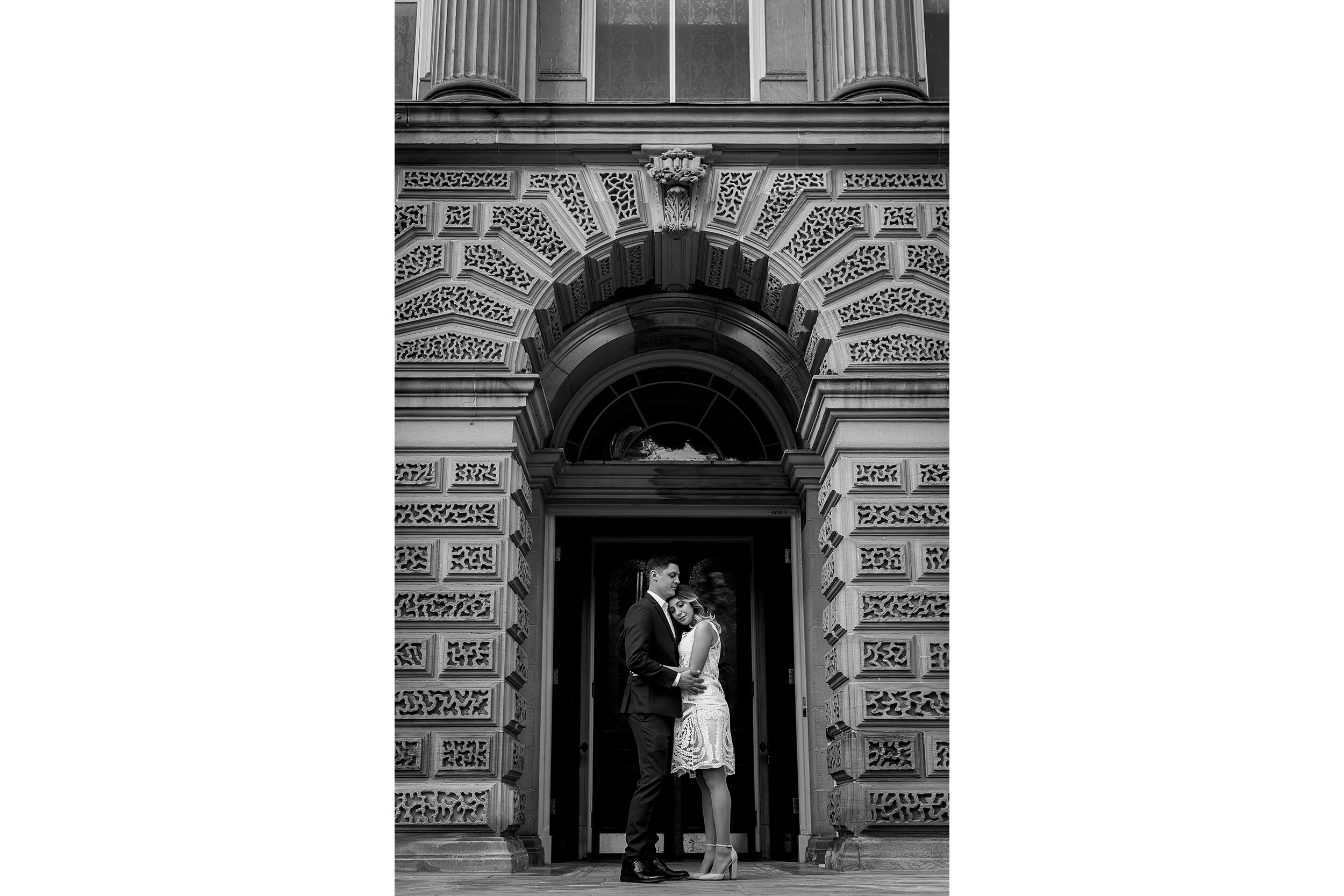 engaged couple pose for a portrait under an arch (Copy)