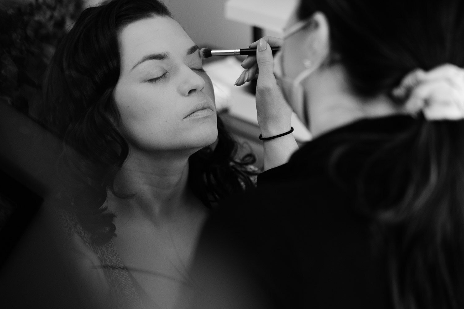 photograph of a bride getting her makeup done before her wedding ceremony