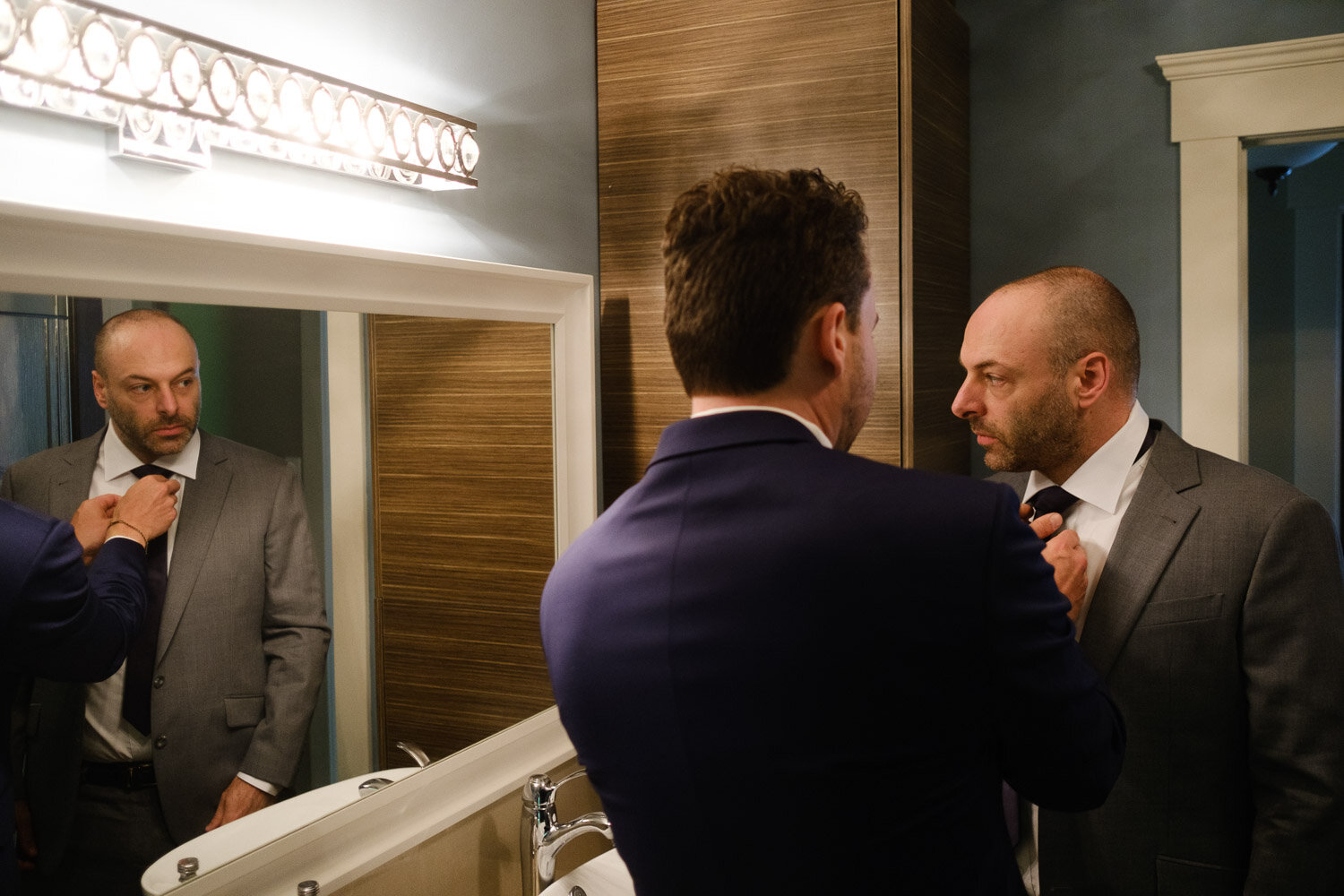 photograph of a groom helping his groomsmen get ready