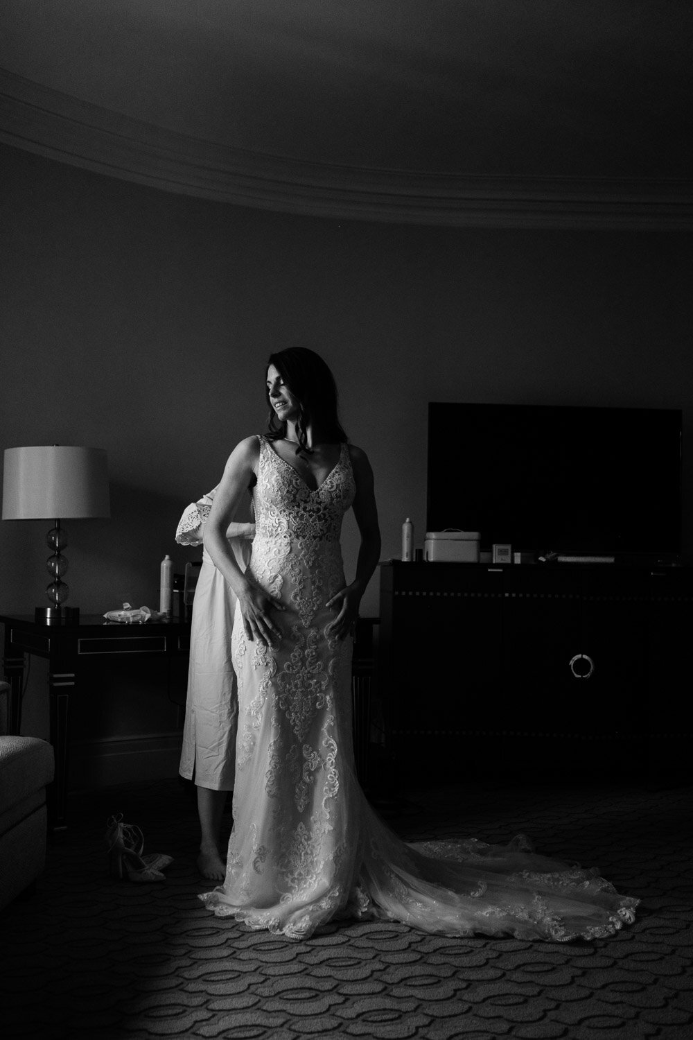 black and white photograph of a bride getting her wedding dress on
