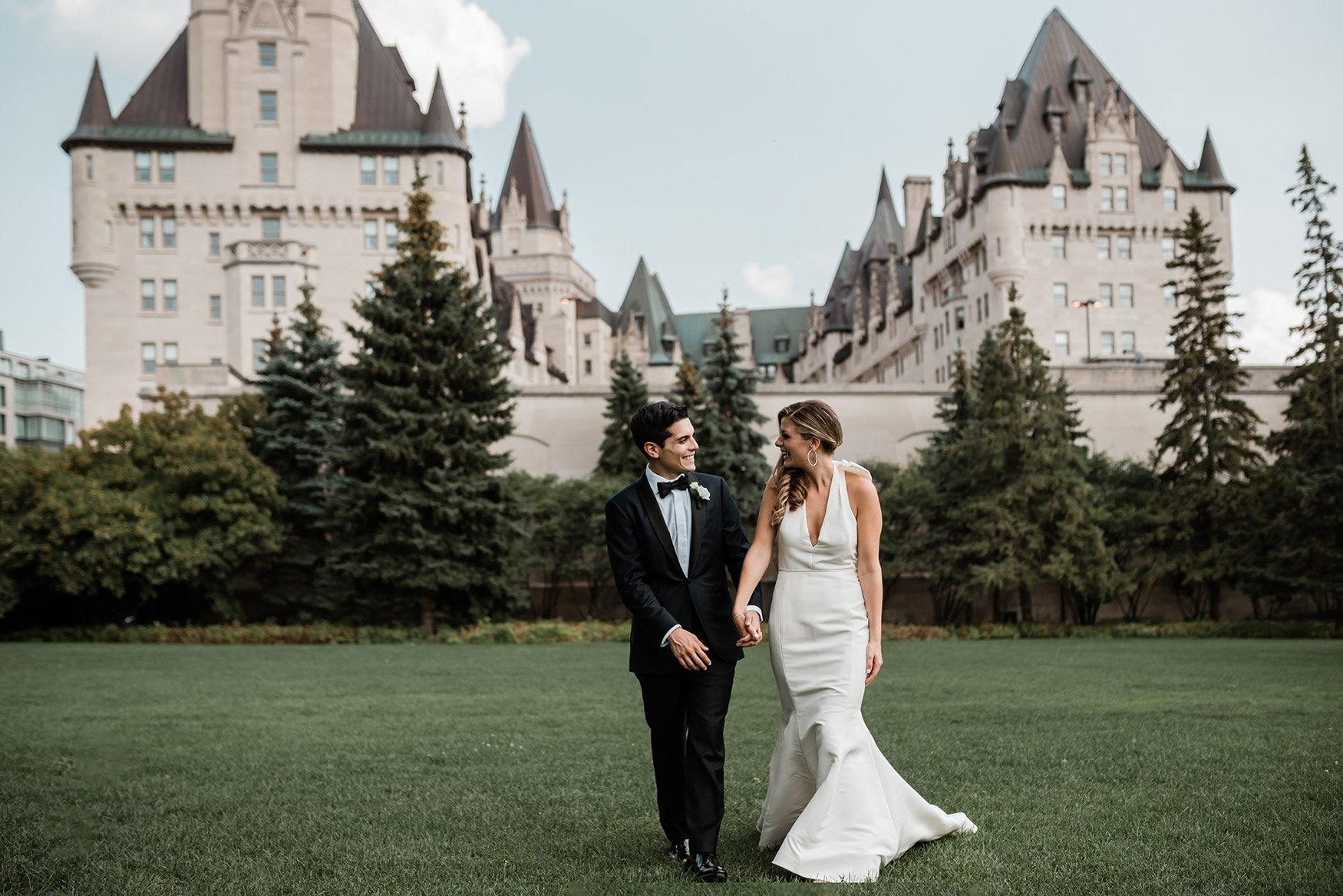 photo of a bride and groom walking in a park with chateau laurier in background (Copy)