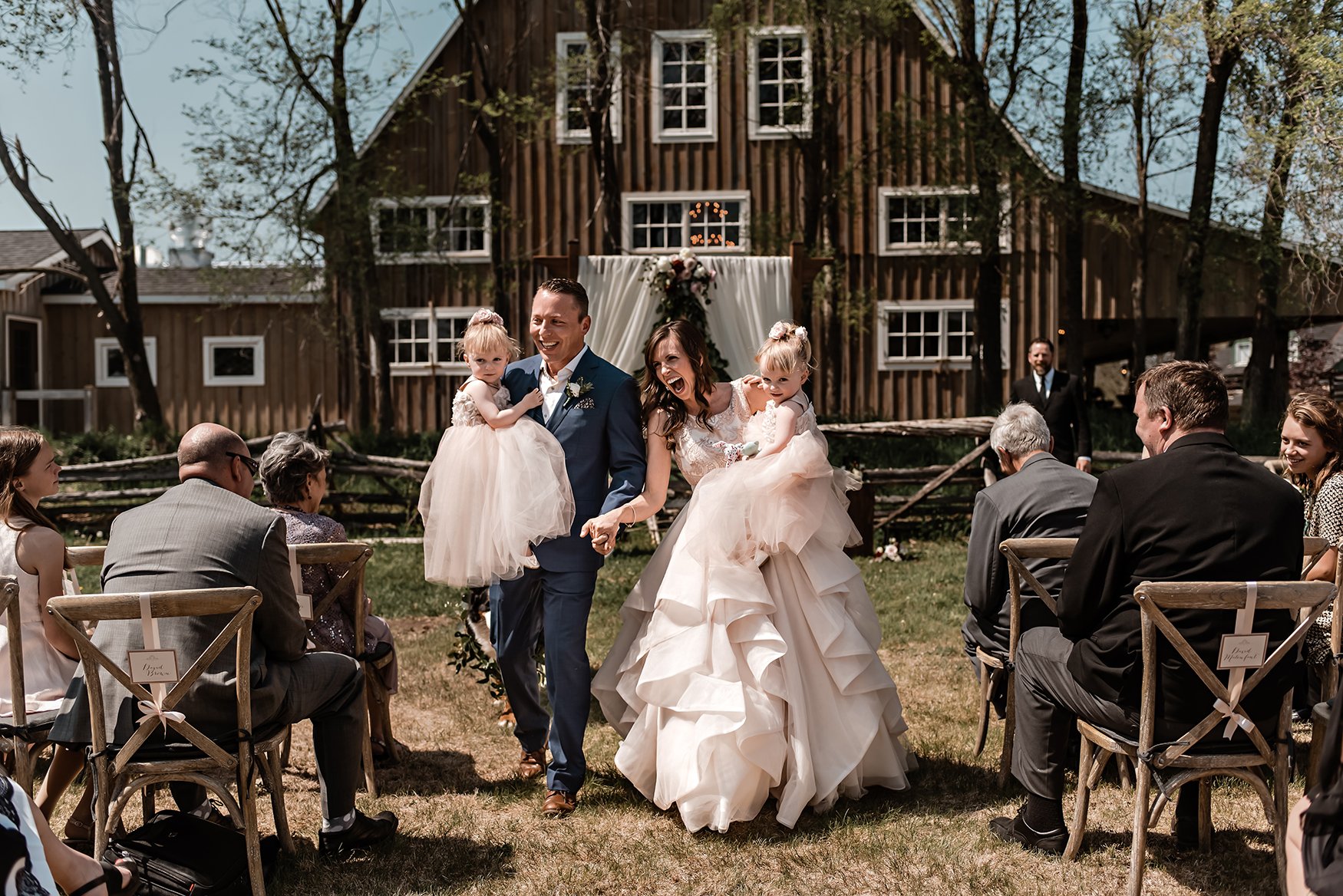 bride and groom walk asile with their twin girls during a wedding ceremony at stonefields in carelton place ontario (Copy)