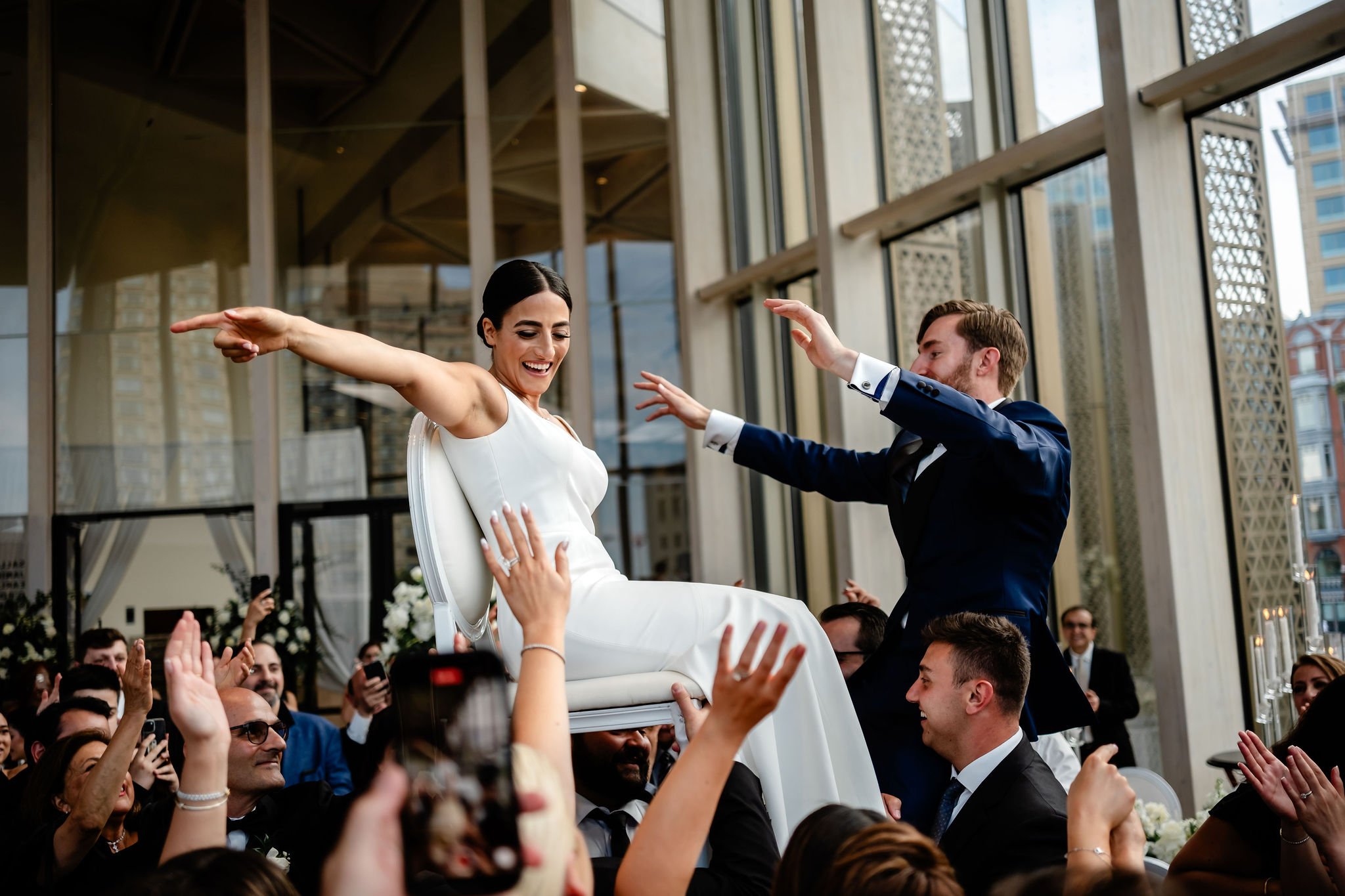 Photo of a bride and groom being raised up on chairs at an National Arts Centre (NAC) wedding reception