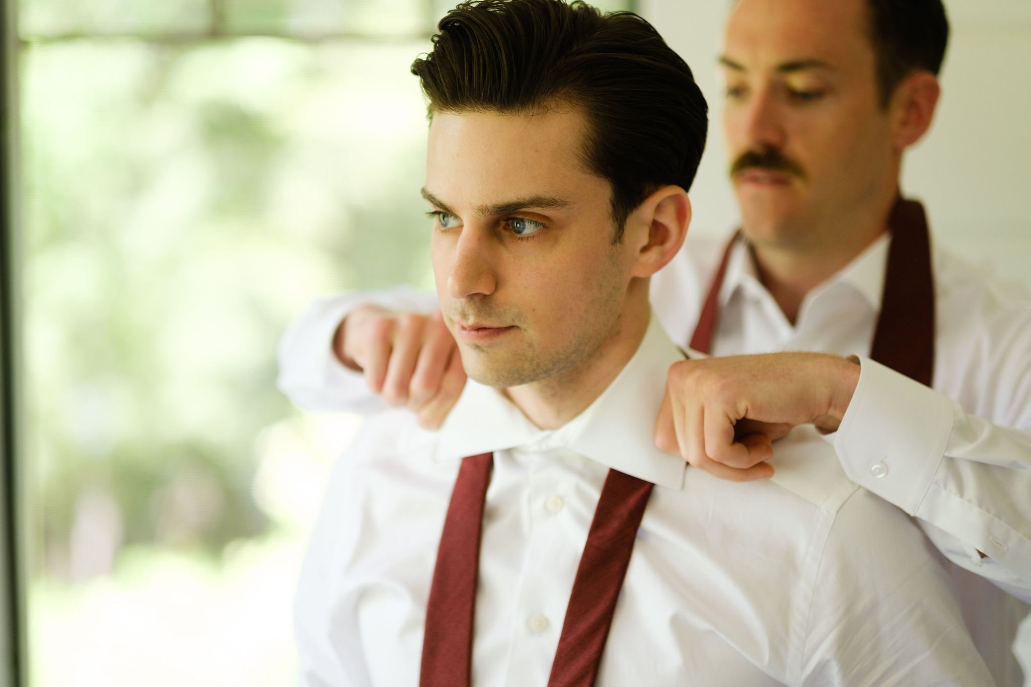  photo of the best man helping the groom get ready 