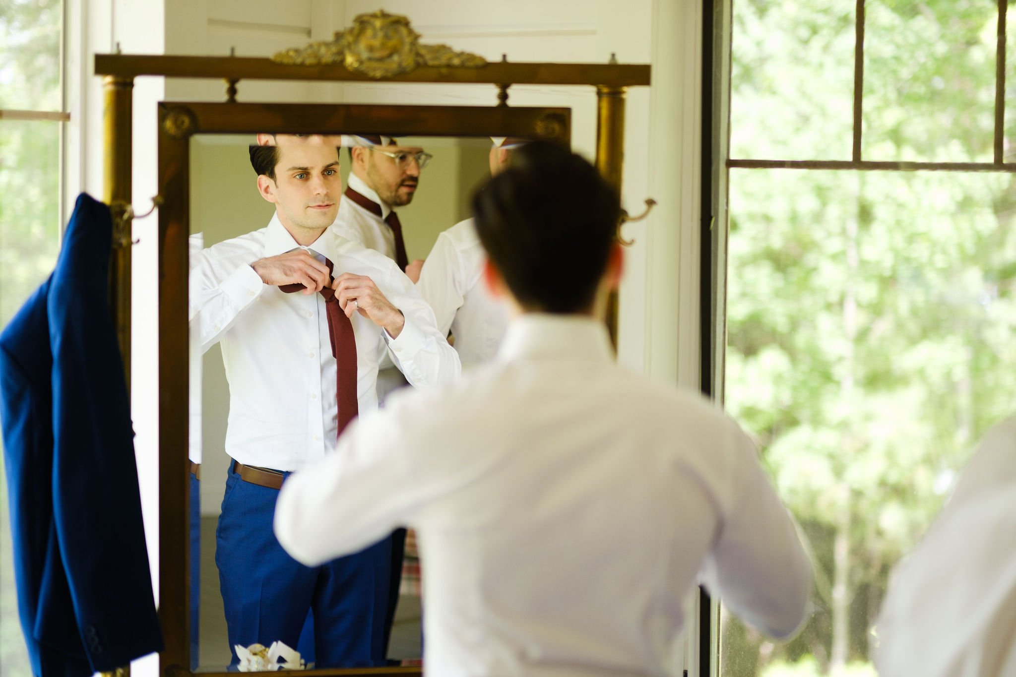  photo of a groom putting on his tie 