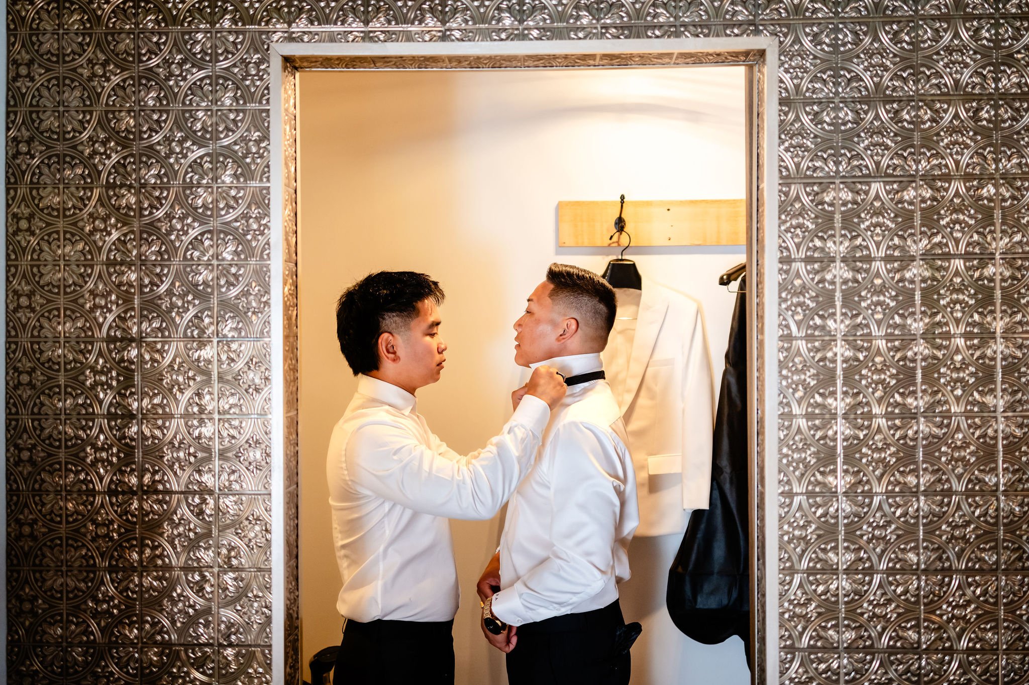 photograph of a best man helping a groom put on his tie