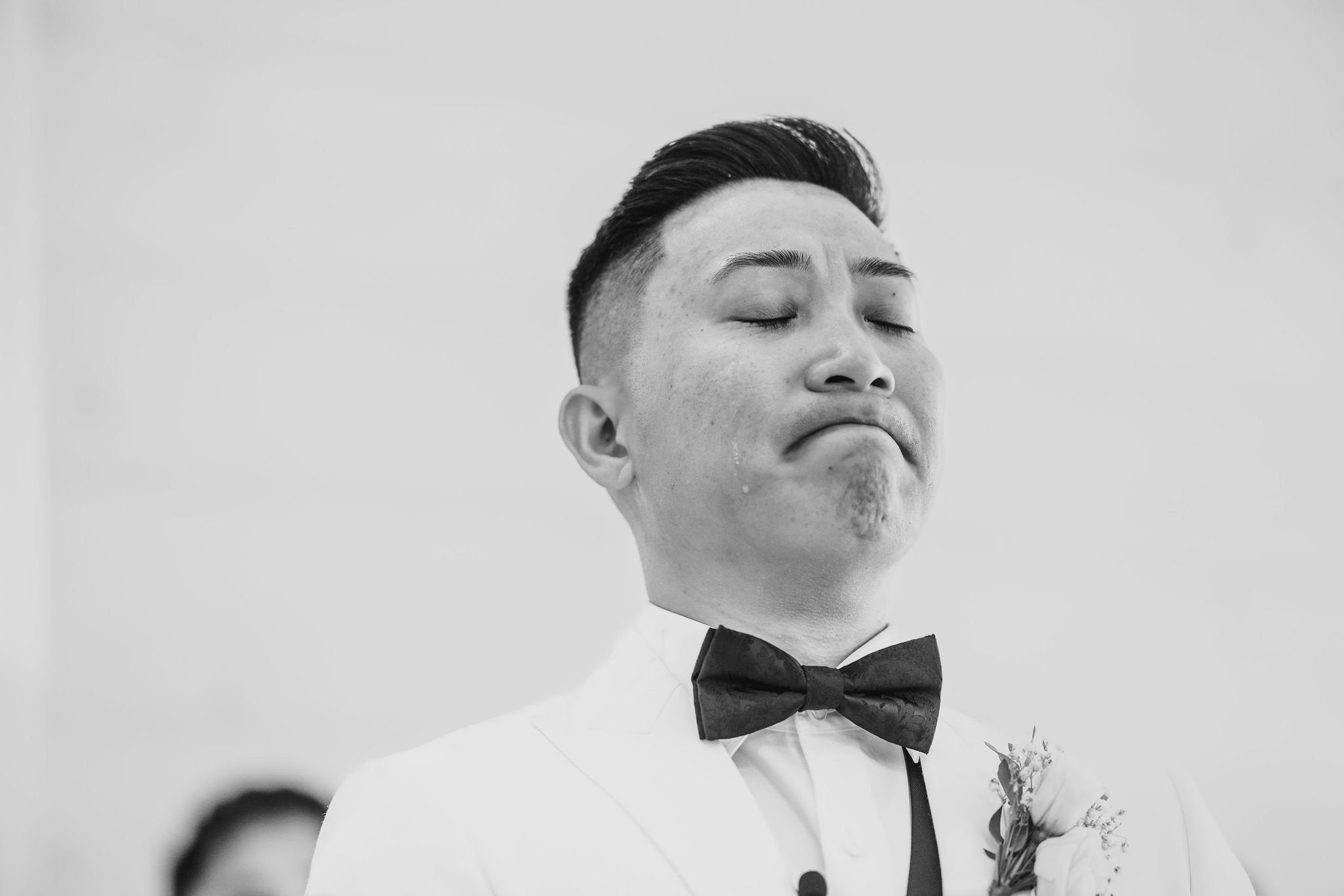 black and white photo of a groom getting emotional seeing his bride walk down the aisle at an indoor wedding at stonefields estate