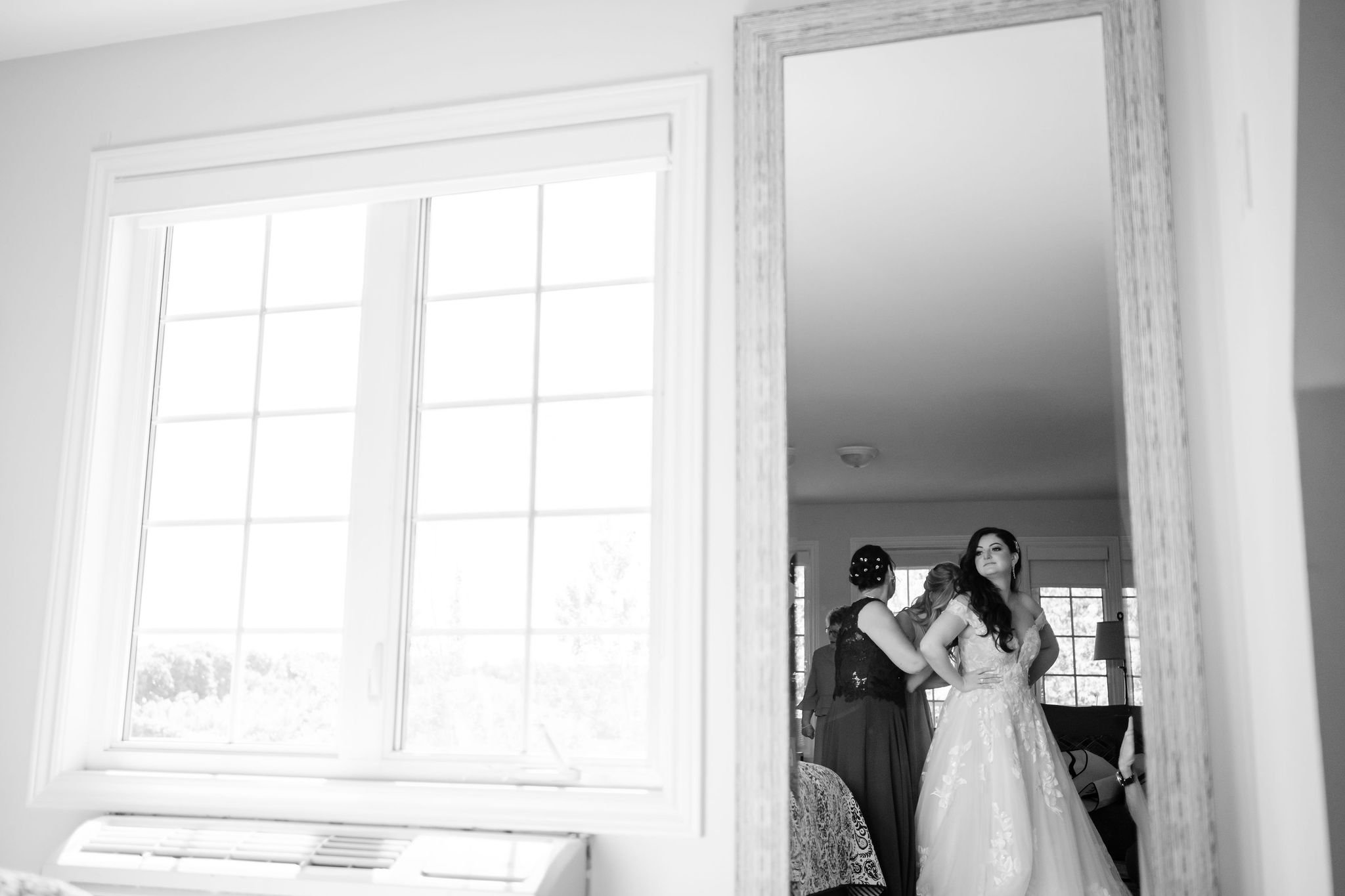 black and white photo of a bride getting in her wedding dress at her Strathmere wedding