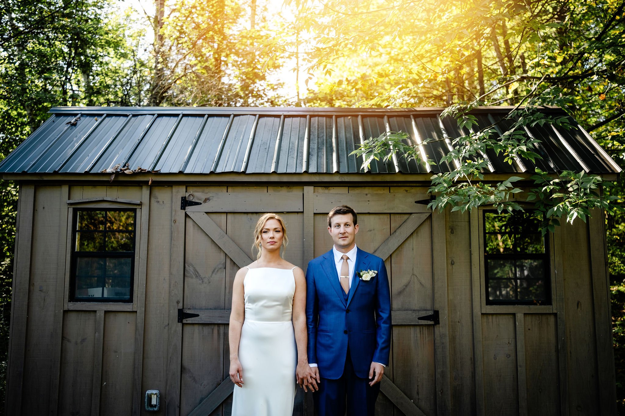 artistic wedding photo of a bride and groom in front of a shed on a fall day.