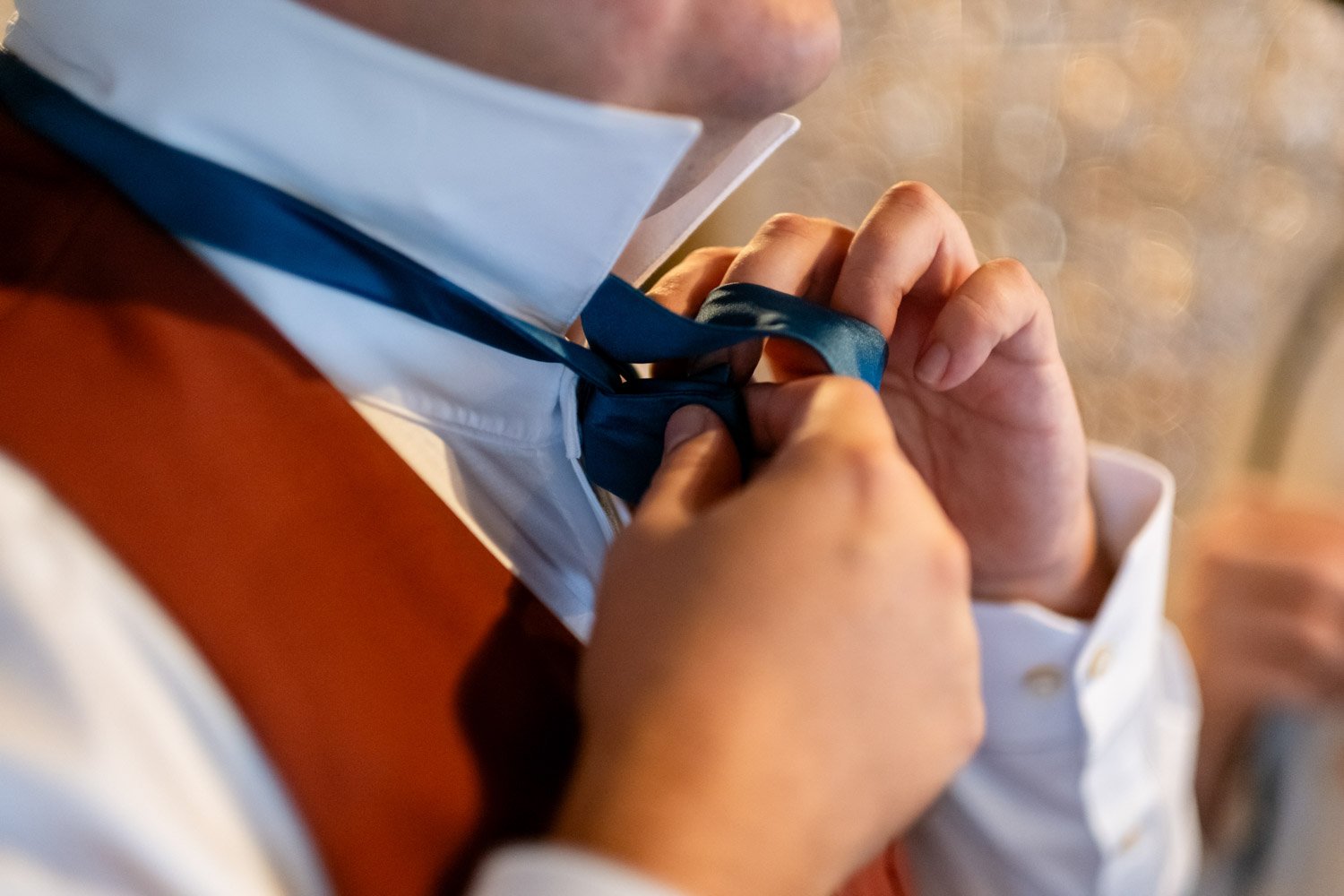 photograph of a groom putting on a bow tie