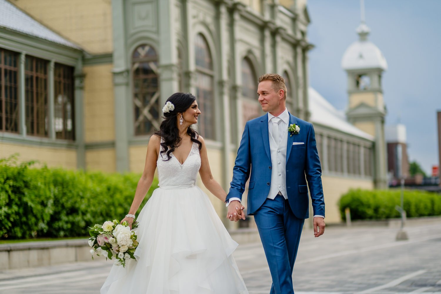 bride and groom walking hand in hand outside the horticulture building at Landsdowne park in ottawa