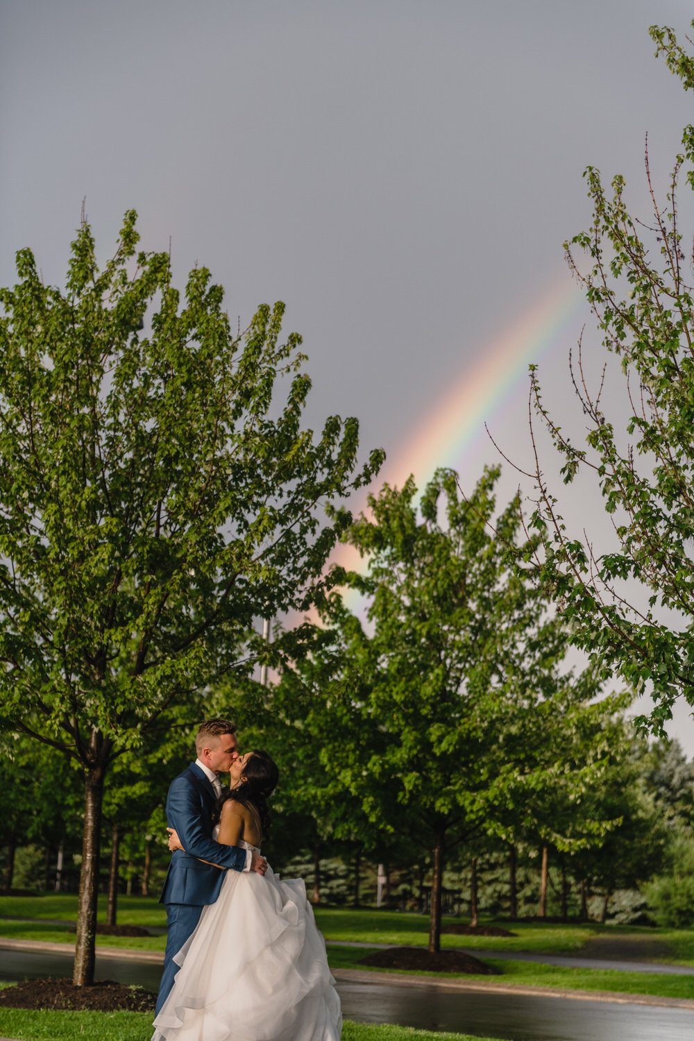 photograph of bride and groom under a rainbow