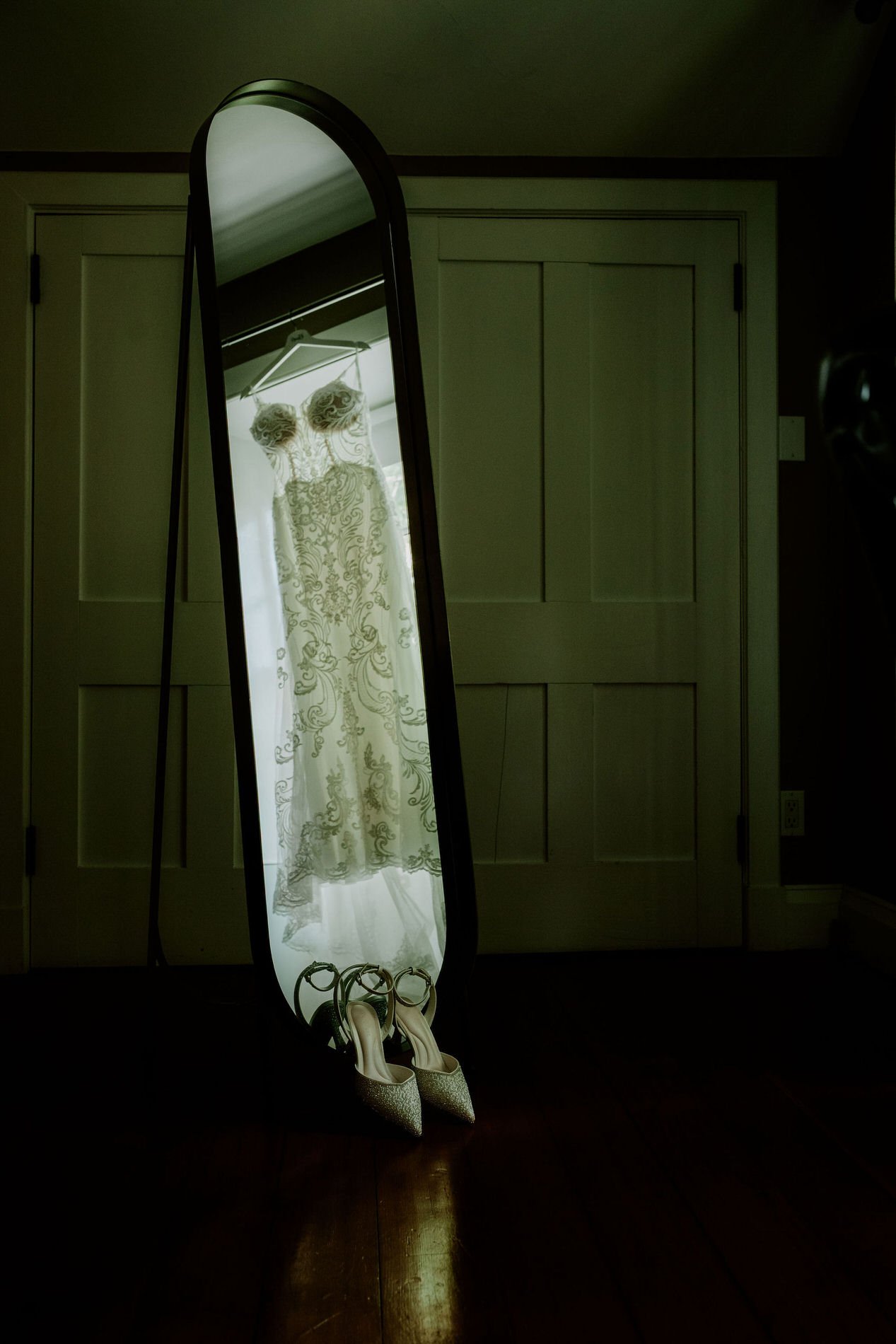 Holly's beaded wedding gown reflected in a tall oval mirror, with sparkly heels at its base