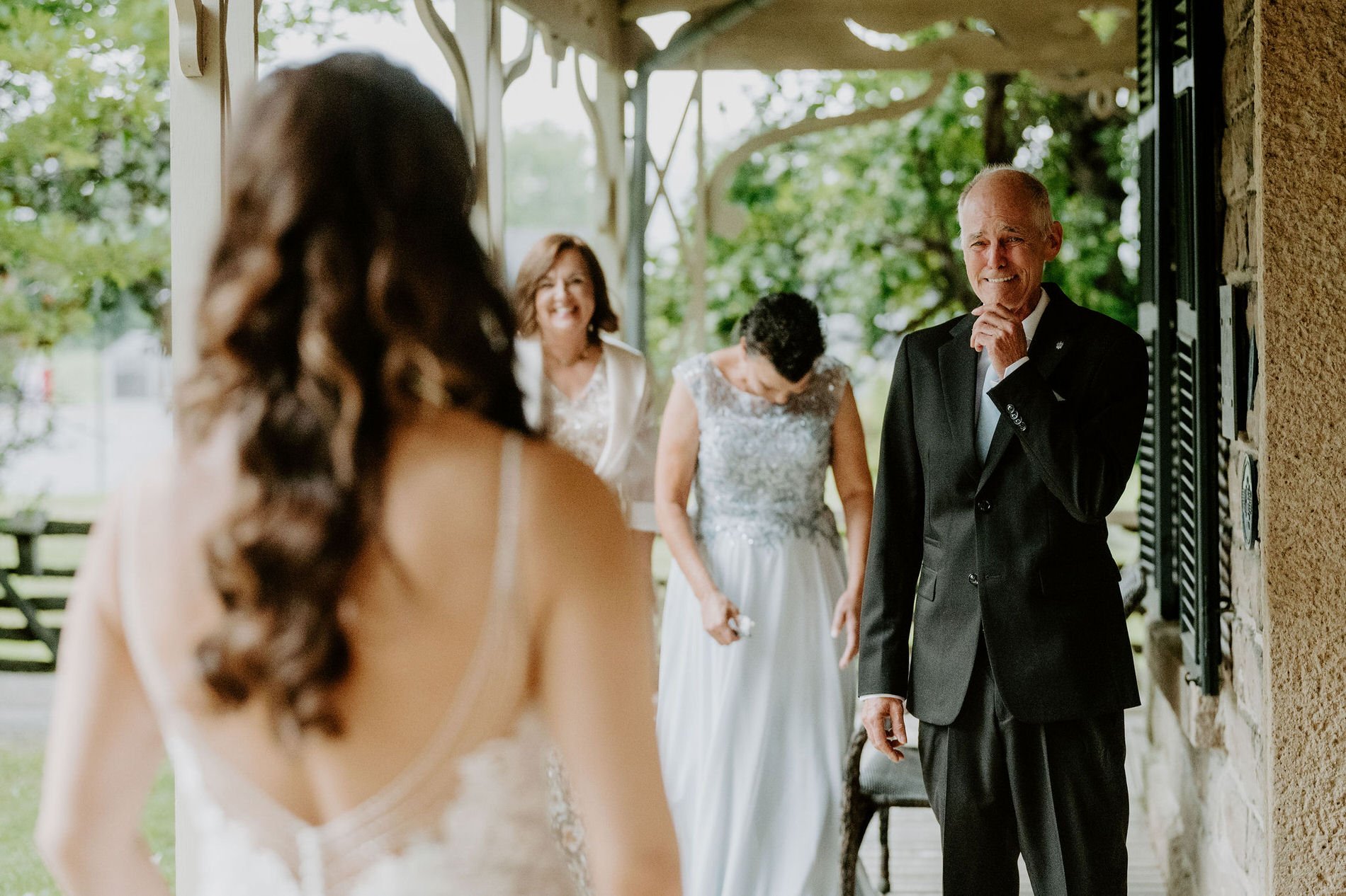 Holly's father smiling as he sees her in her gown for the first time on the porch at Evermore in Ottawa