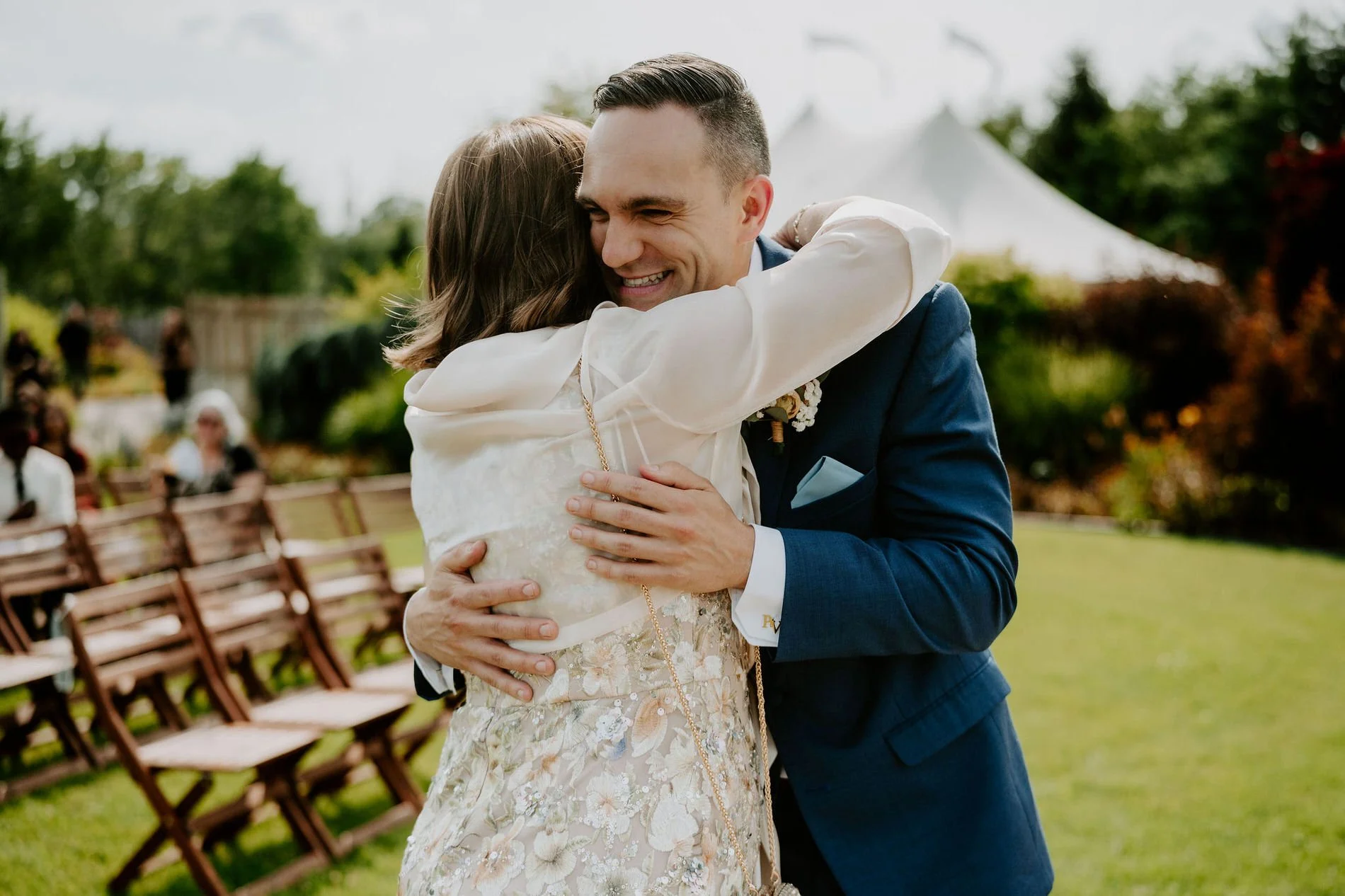 Petar hugging a woman in a floral dress beside the ceremony chairs on the lawn at Evermore