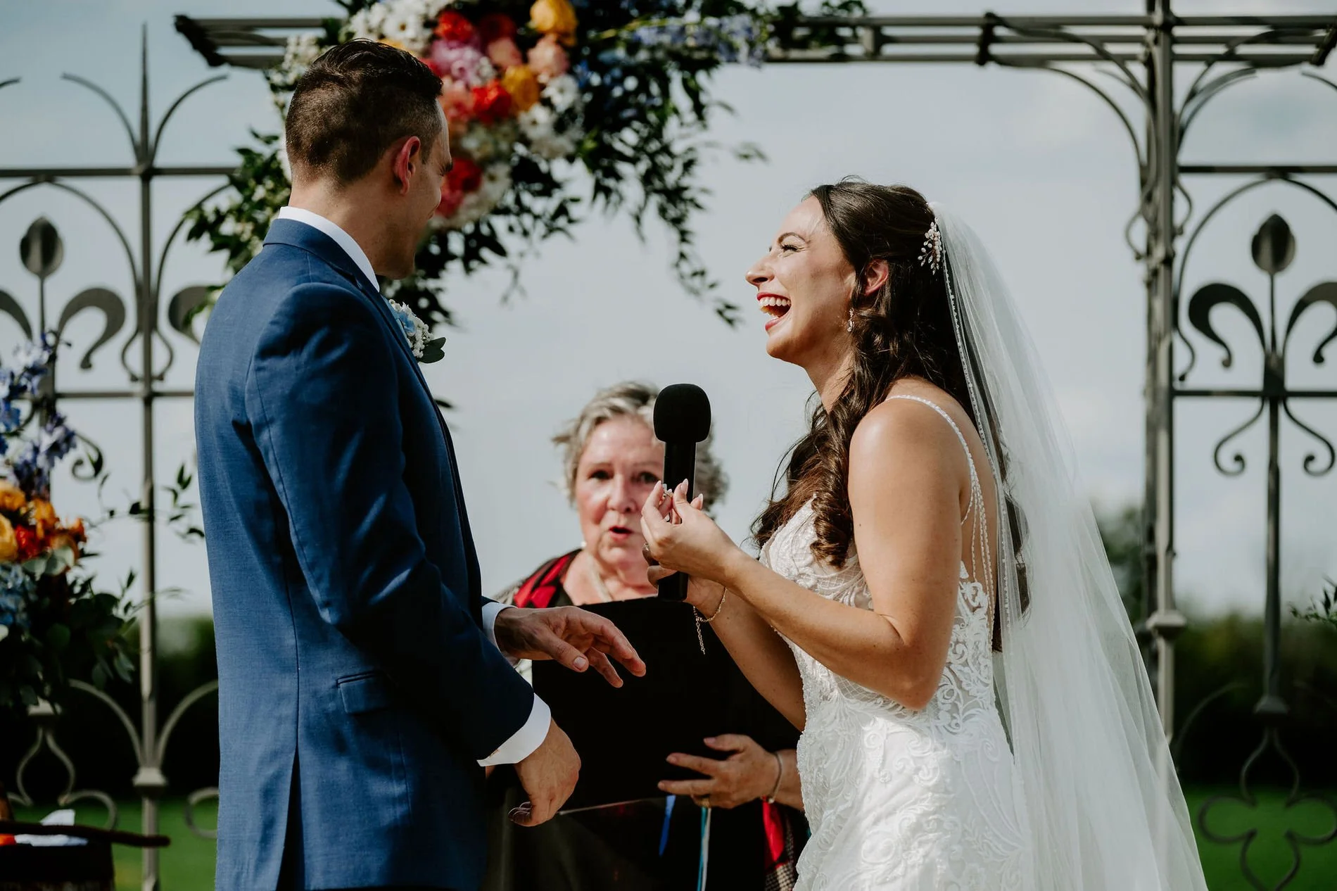 Holly laughing as she reads her vows into a microphone at Evermore