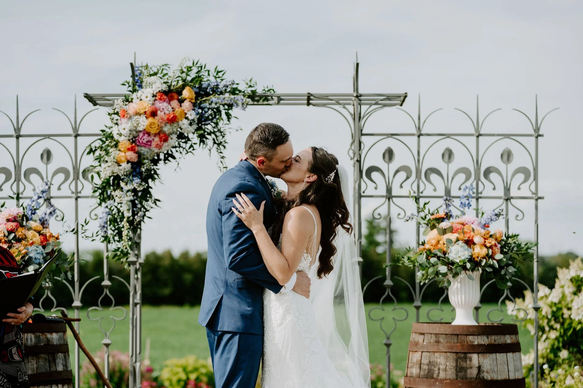 Holly and Petar's first kiss under the flower-covered wrought-iron arch at Evermore in Ottawa
