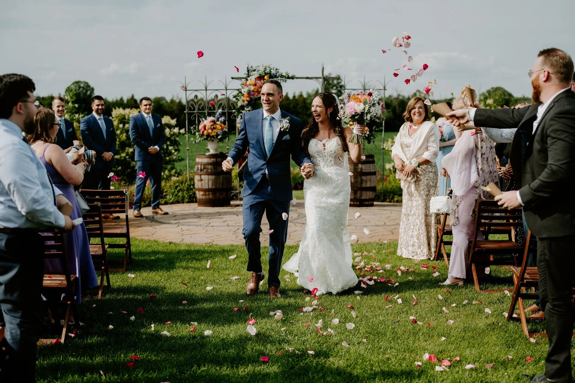 Holly and Petar walking back up the aisle hand in hand as guests throw rose petals at Evermore