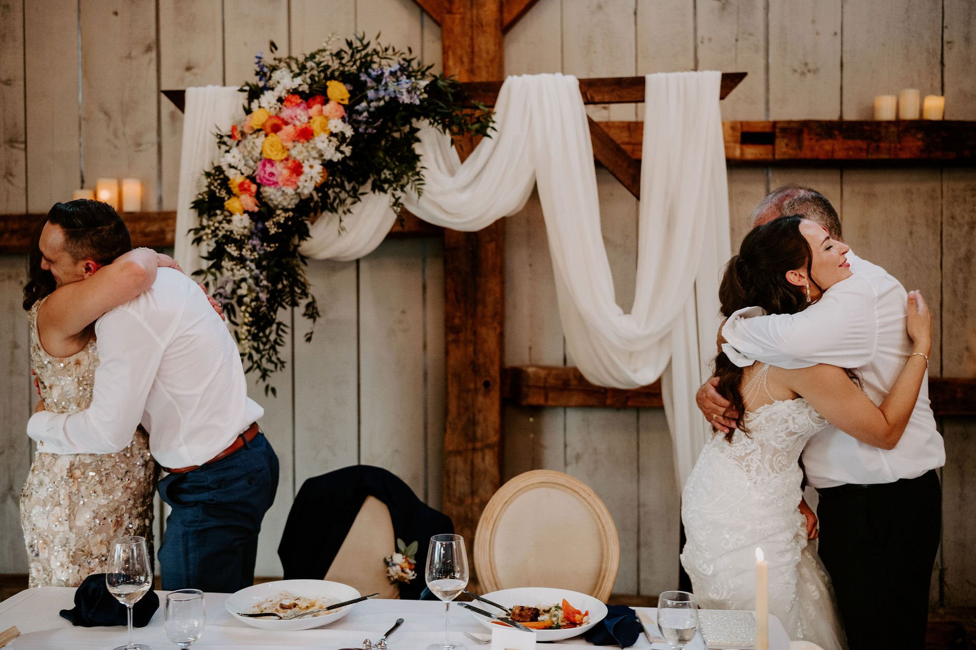 Holly and Petar each hugging a family member at the head table after the speeches
