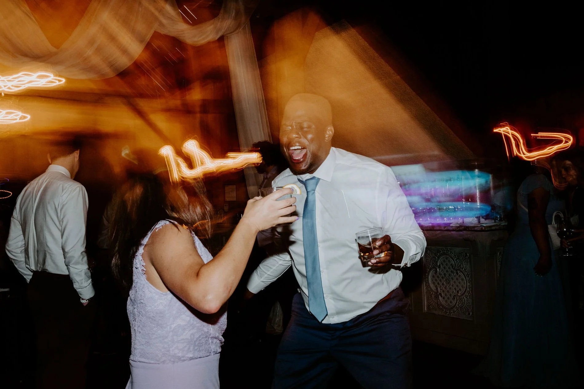 Groomsman shouting with joy as he dances with a guest, drink in hand, at Holly and Petar's Ottawa wedding