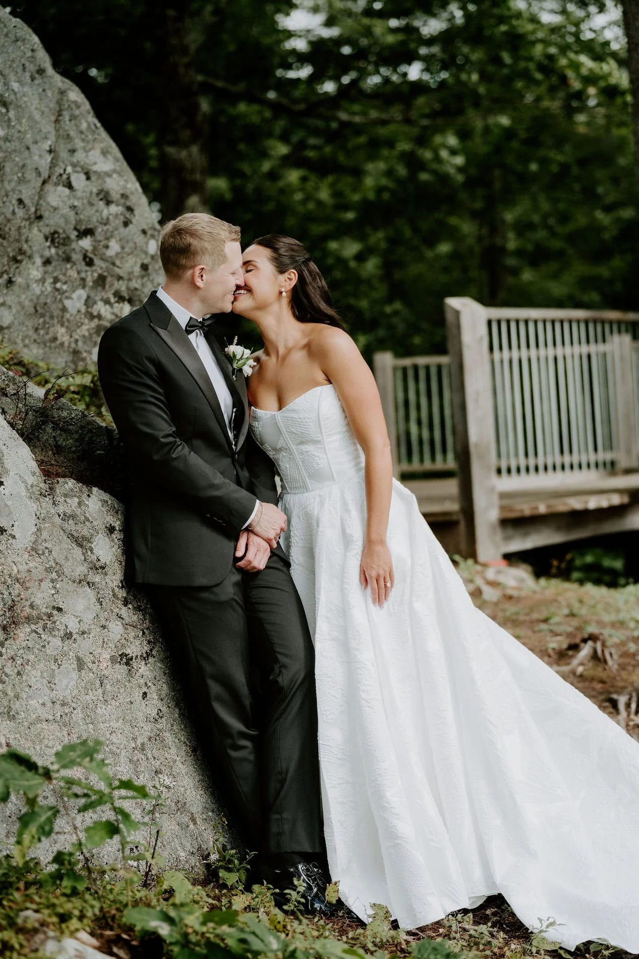 Kylie and Will kissing as they lean against a granite boulder at Le Belvedere