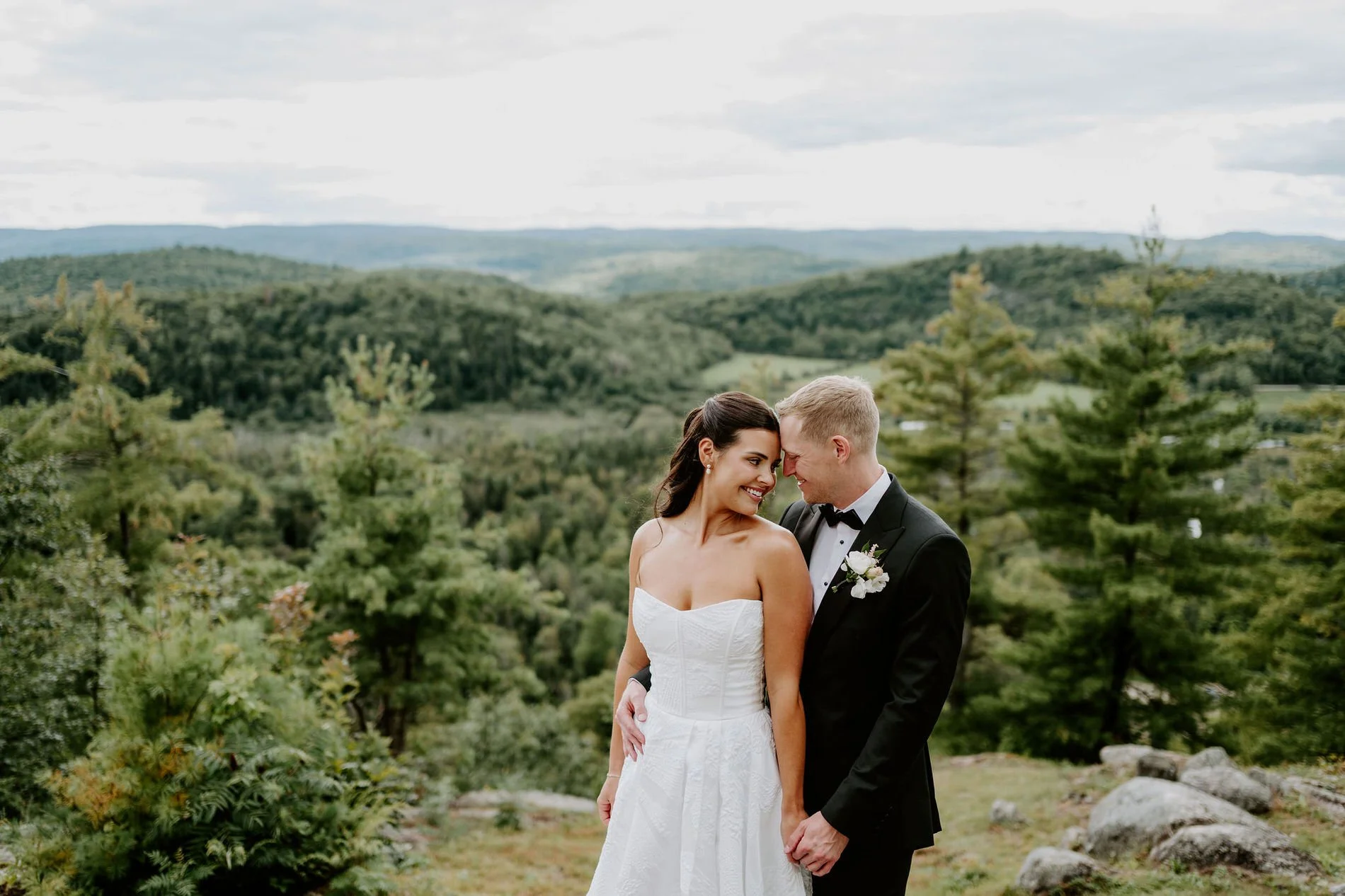 Kylie and Will smiling cheek to cheek above the rolling Gatineau Hills near Wakefield, Quebec