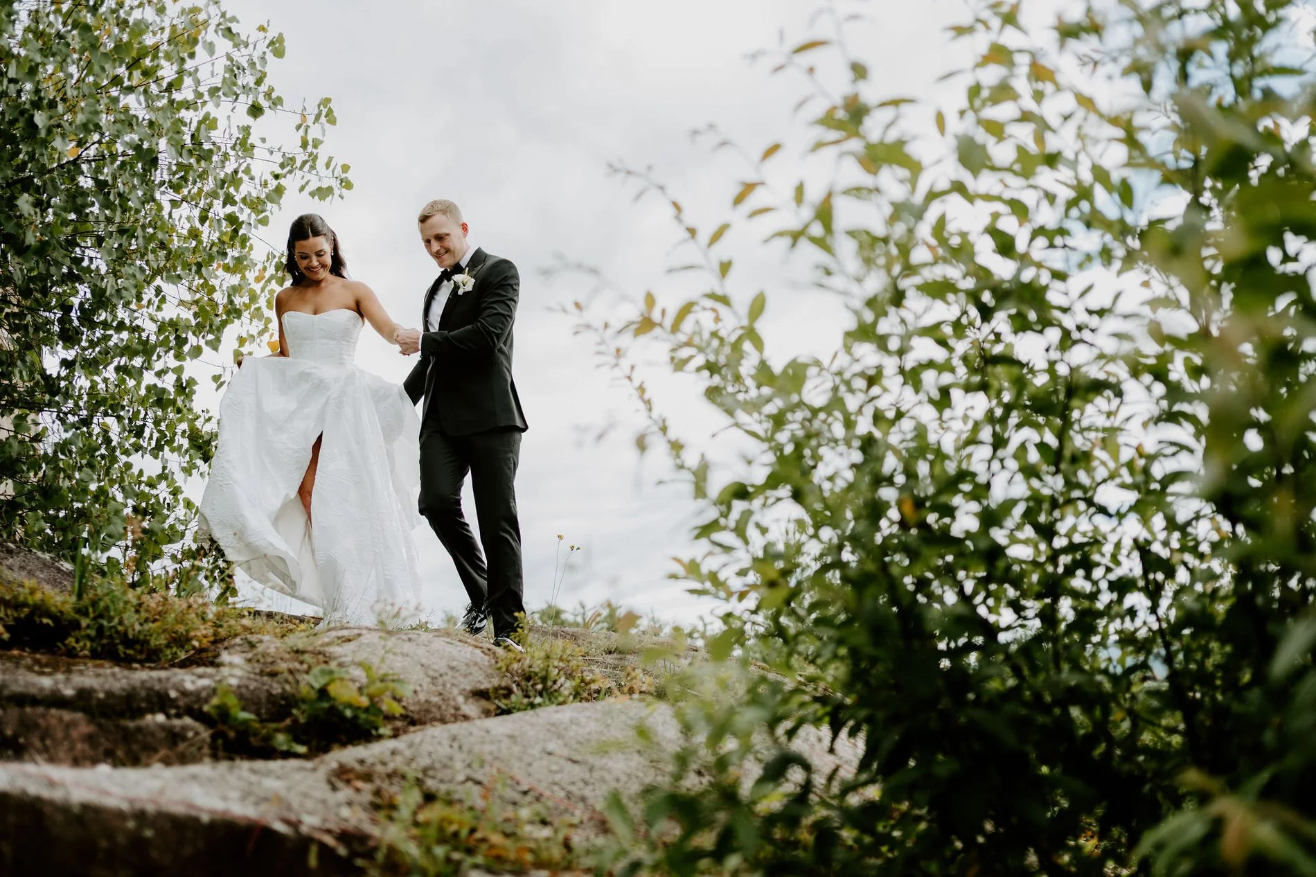 Will helping Kylie across the granite rocks at Le Belvedere, framed by leafy branches