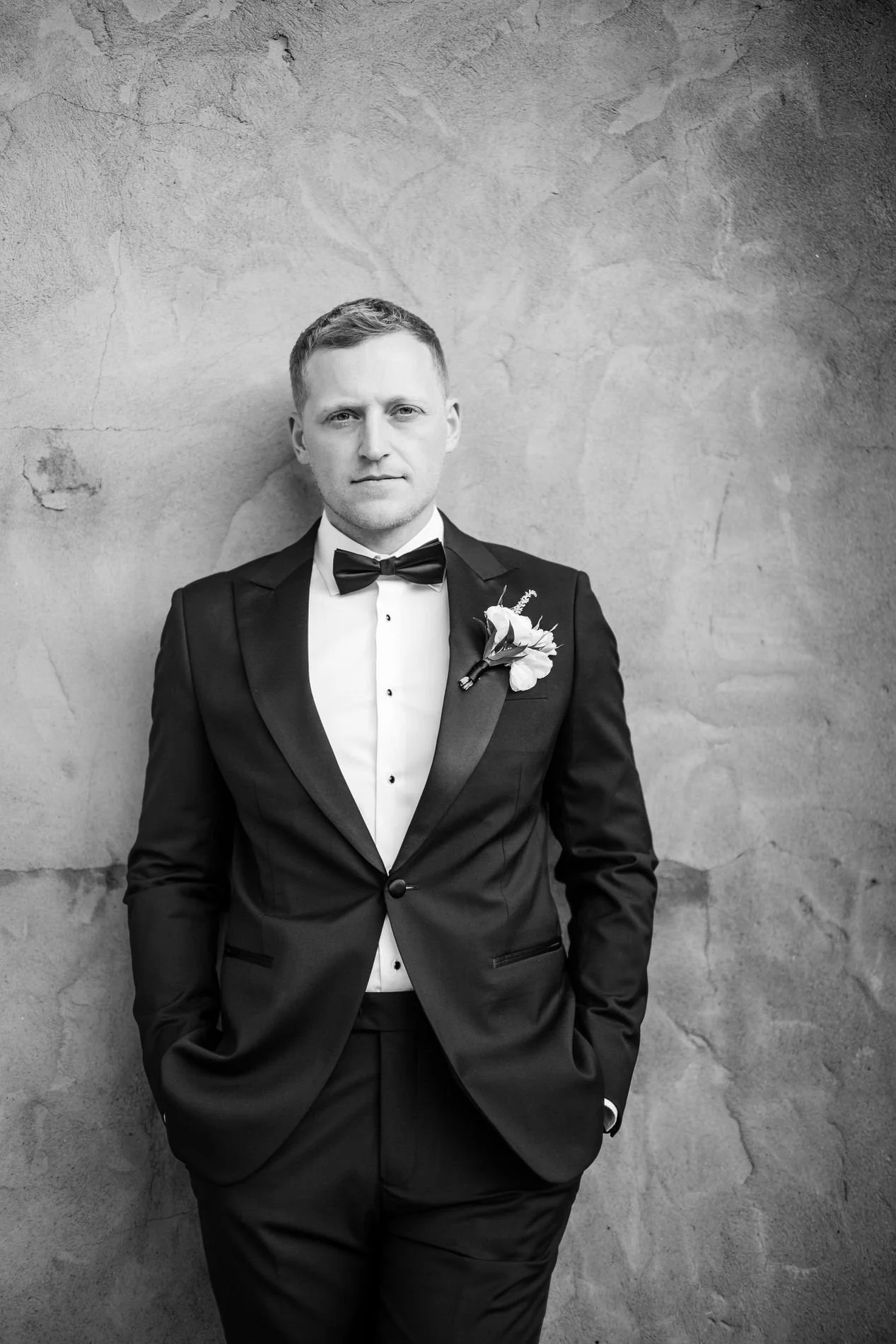 Black and white portrait of Will in his tuxedo against a textured wall