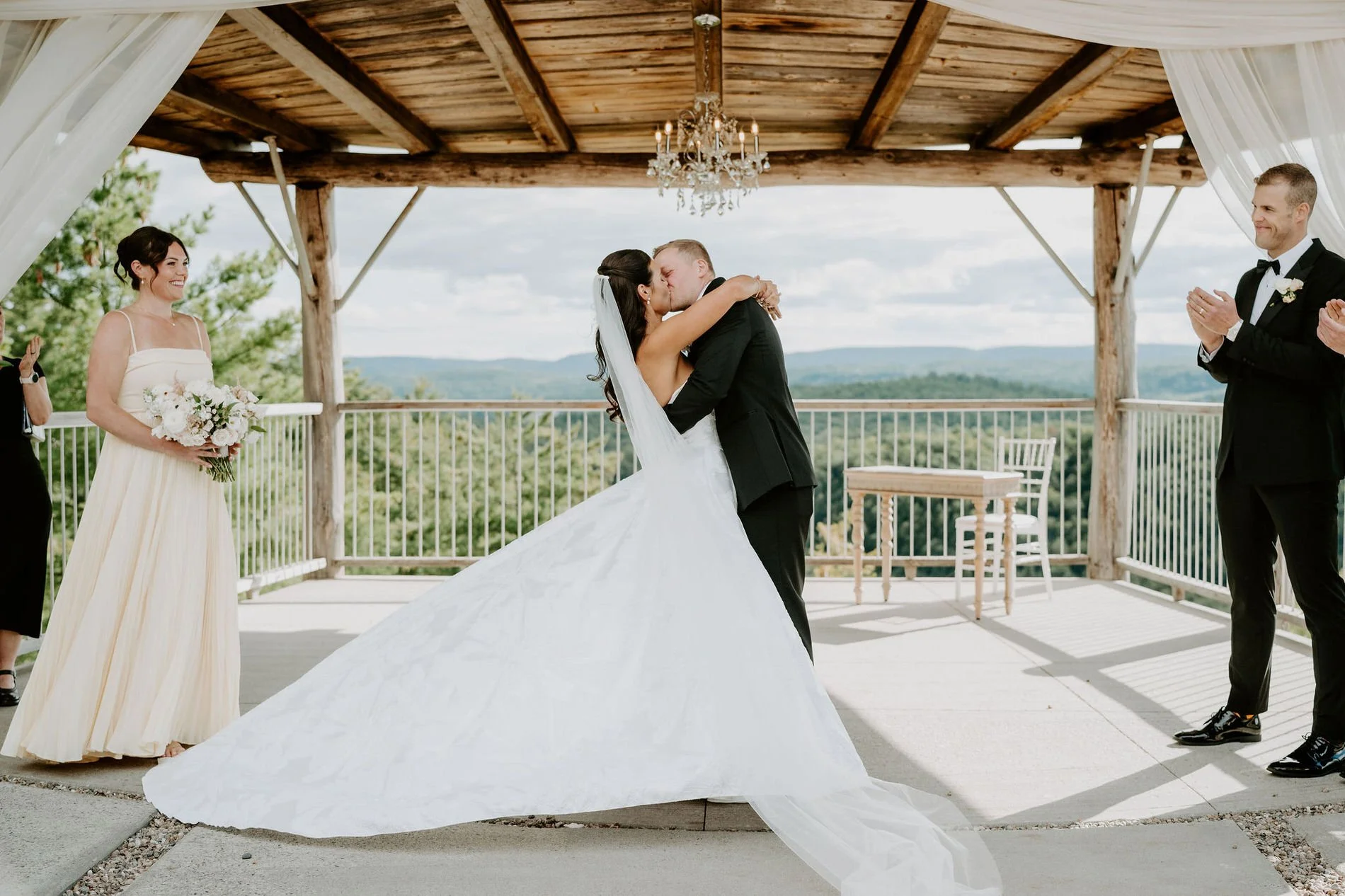 Kylie and Will's first kiss under the draped pavilion at Le Belvedere, the Gatineau Hills behind them