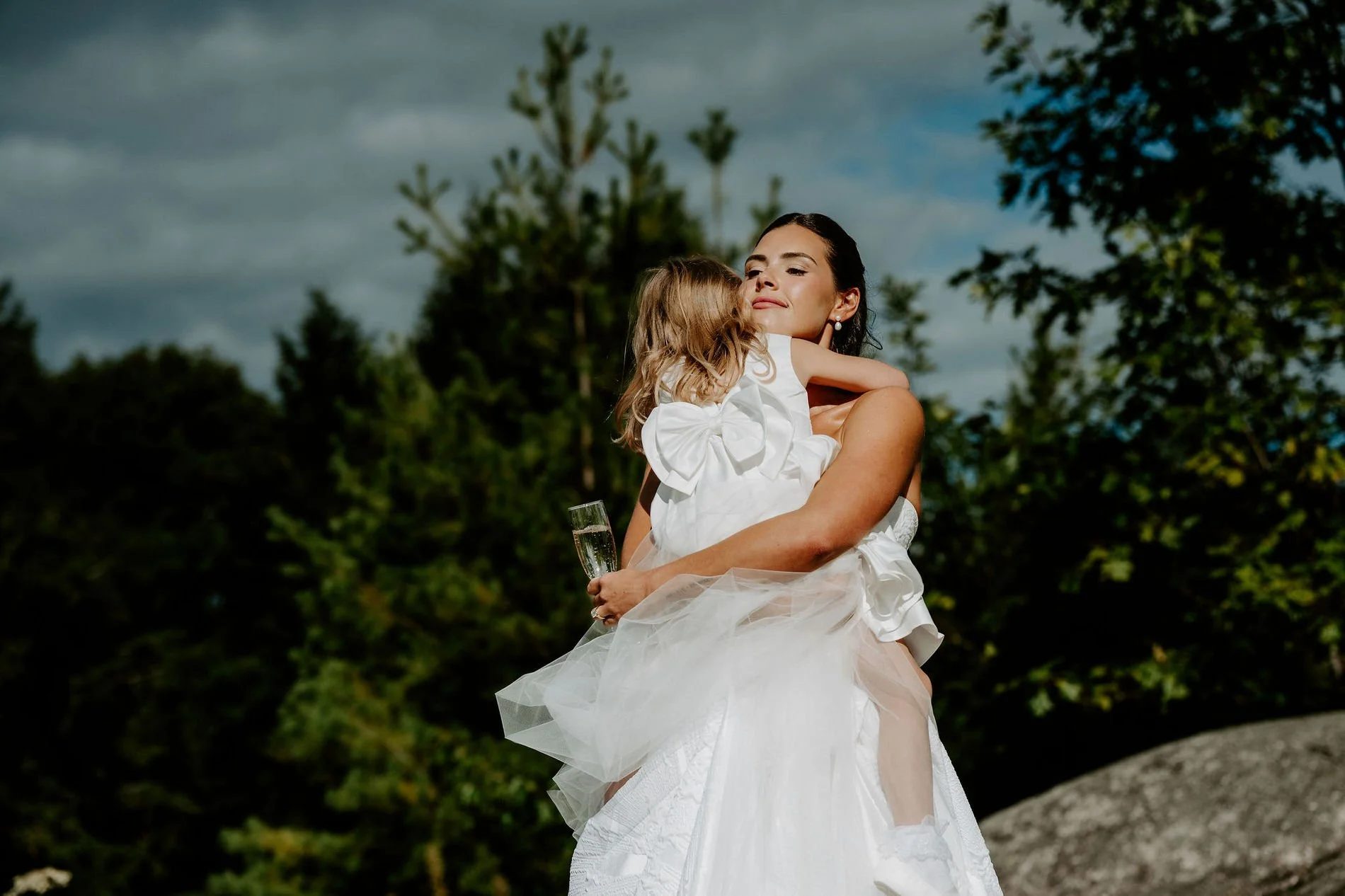 Kylie hugging a little flower girl in a white tulle dress after the ceremony