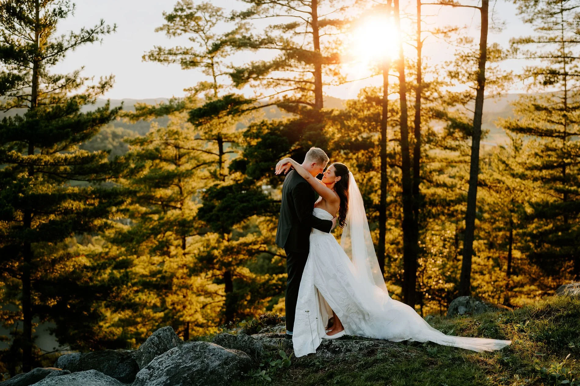 Kylie and Will embracing among the pines at sunset at Le Belvedere in Wakefield, Quebec