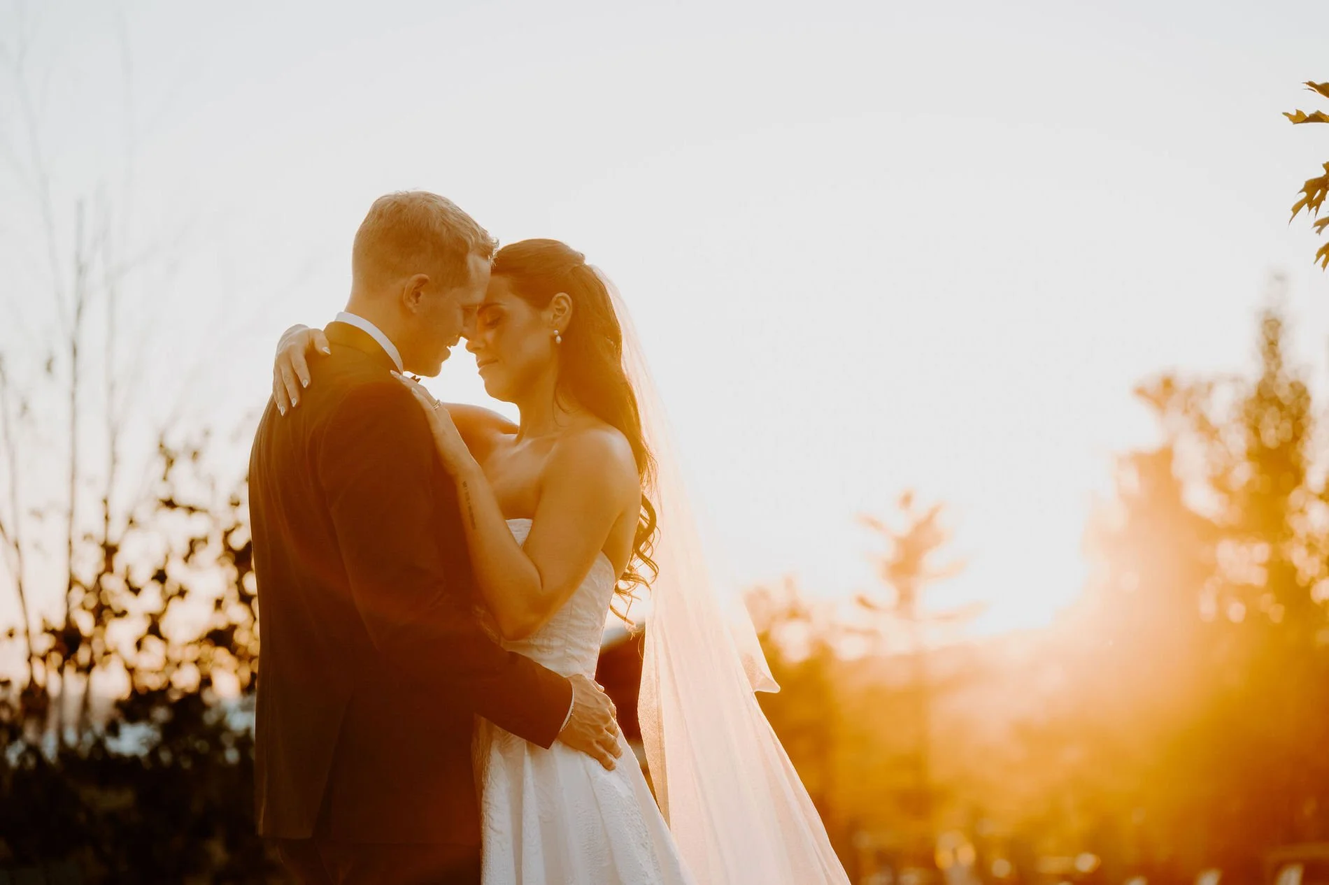 Kylie and Will forehead to forehead against a glowing sunset near Ottawa