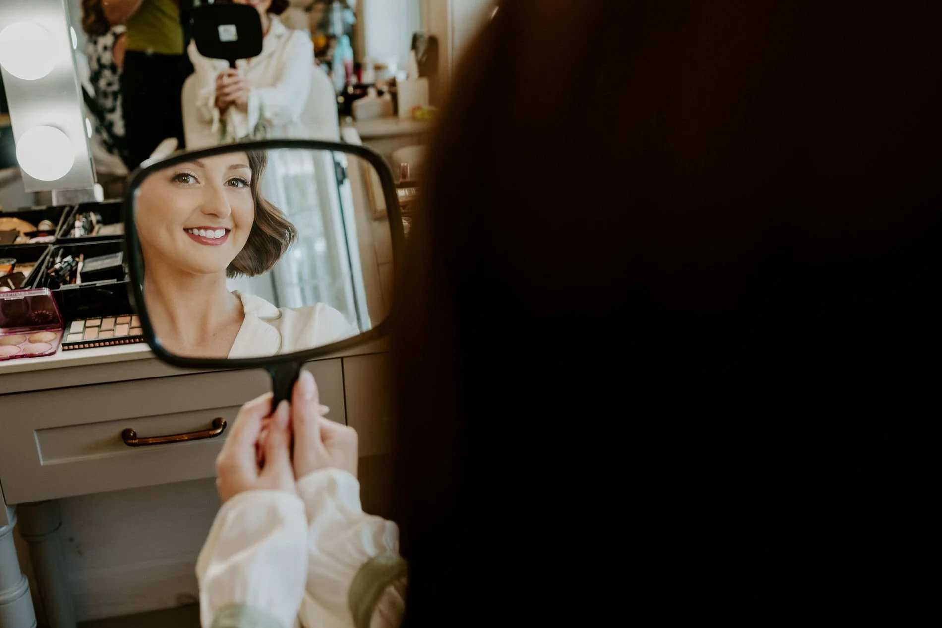 Emily smiling at her finished makeup in a hand mirror