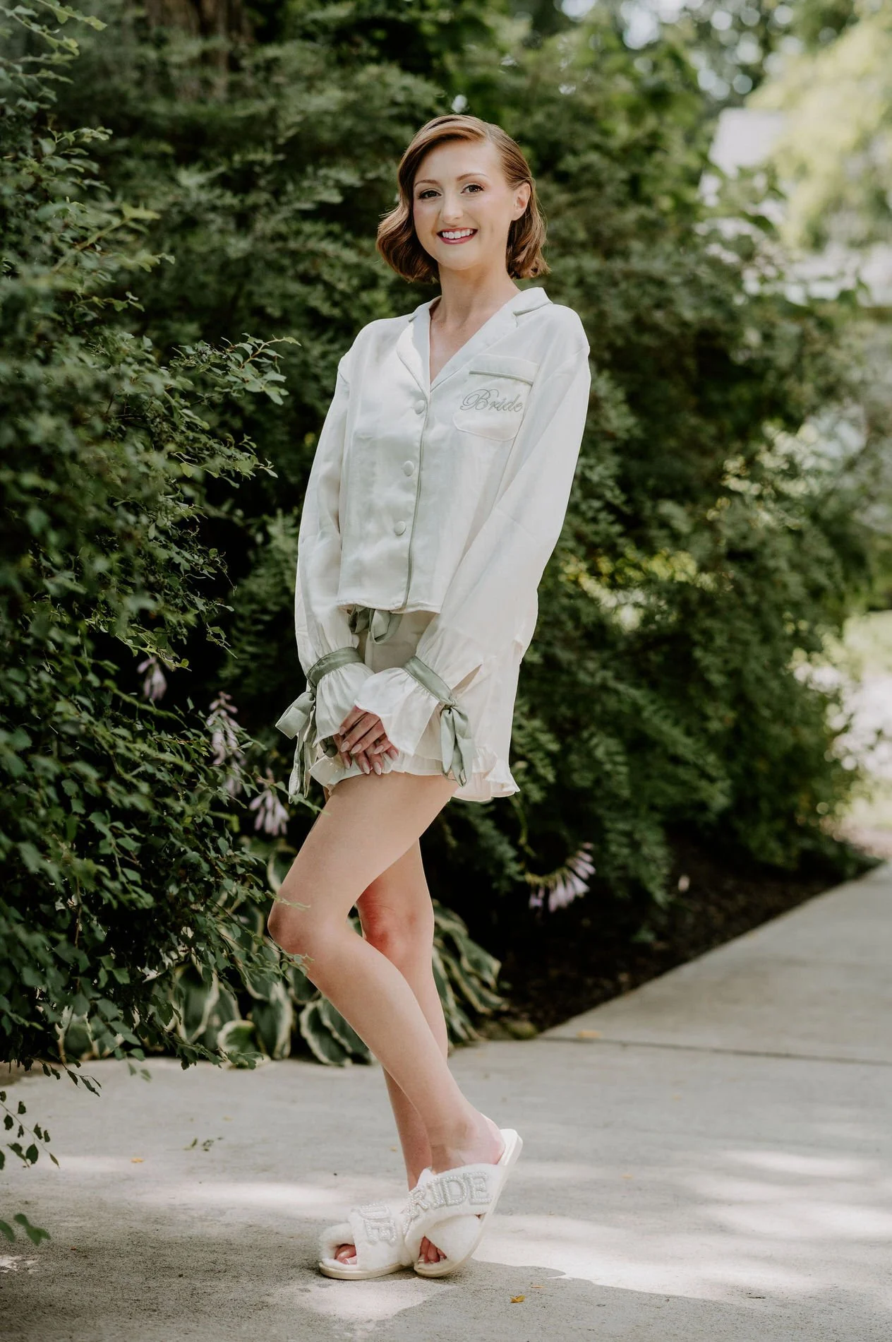 Emily in "Bride" pyjamas and slippers smiling on a garden path