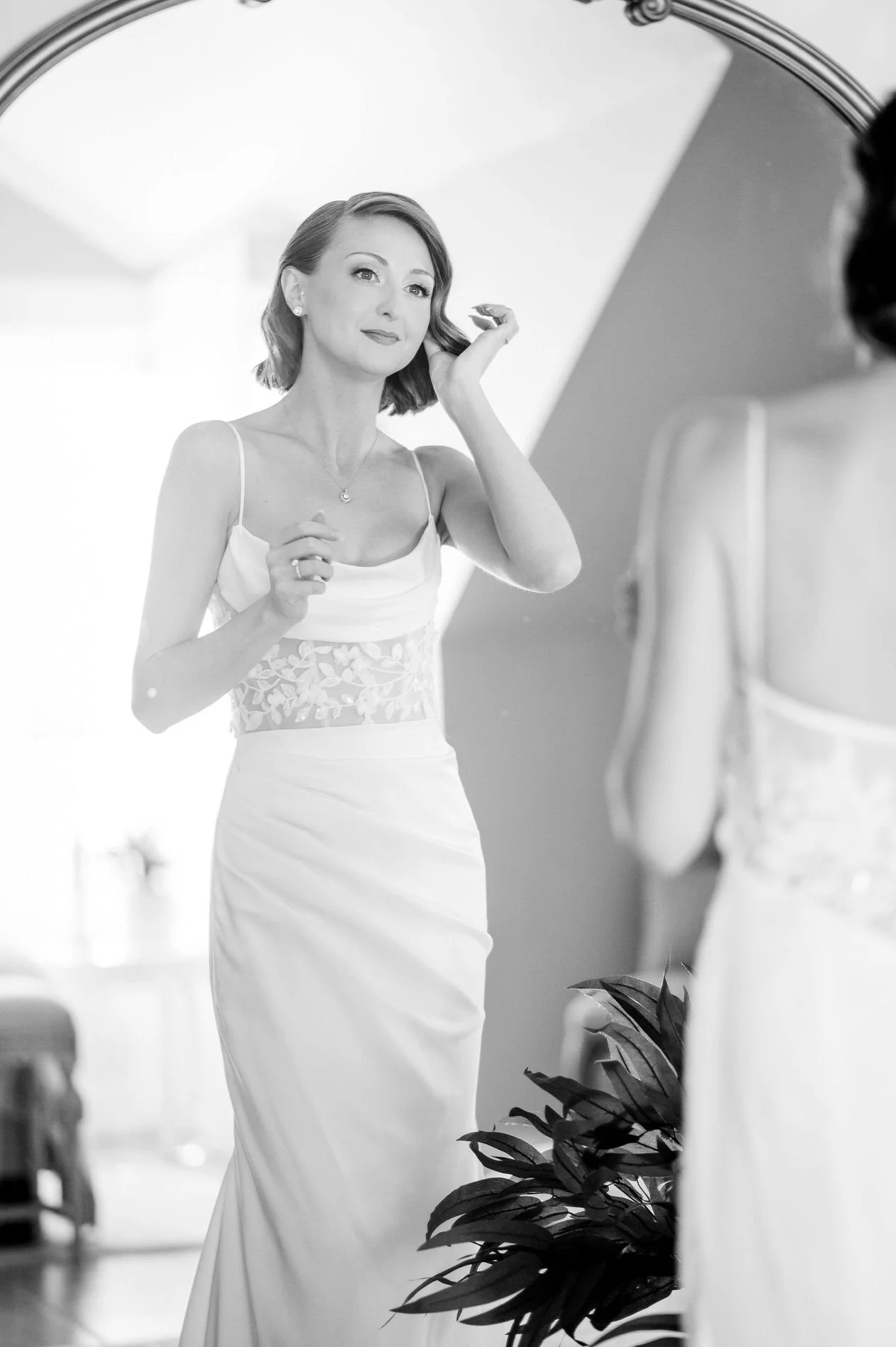 Black and white photo of Emily adjusting her earring in the mirror