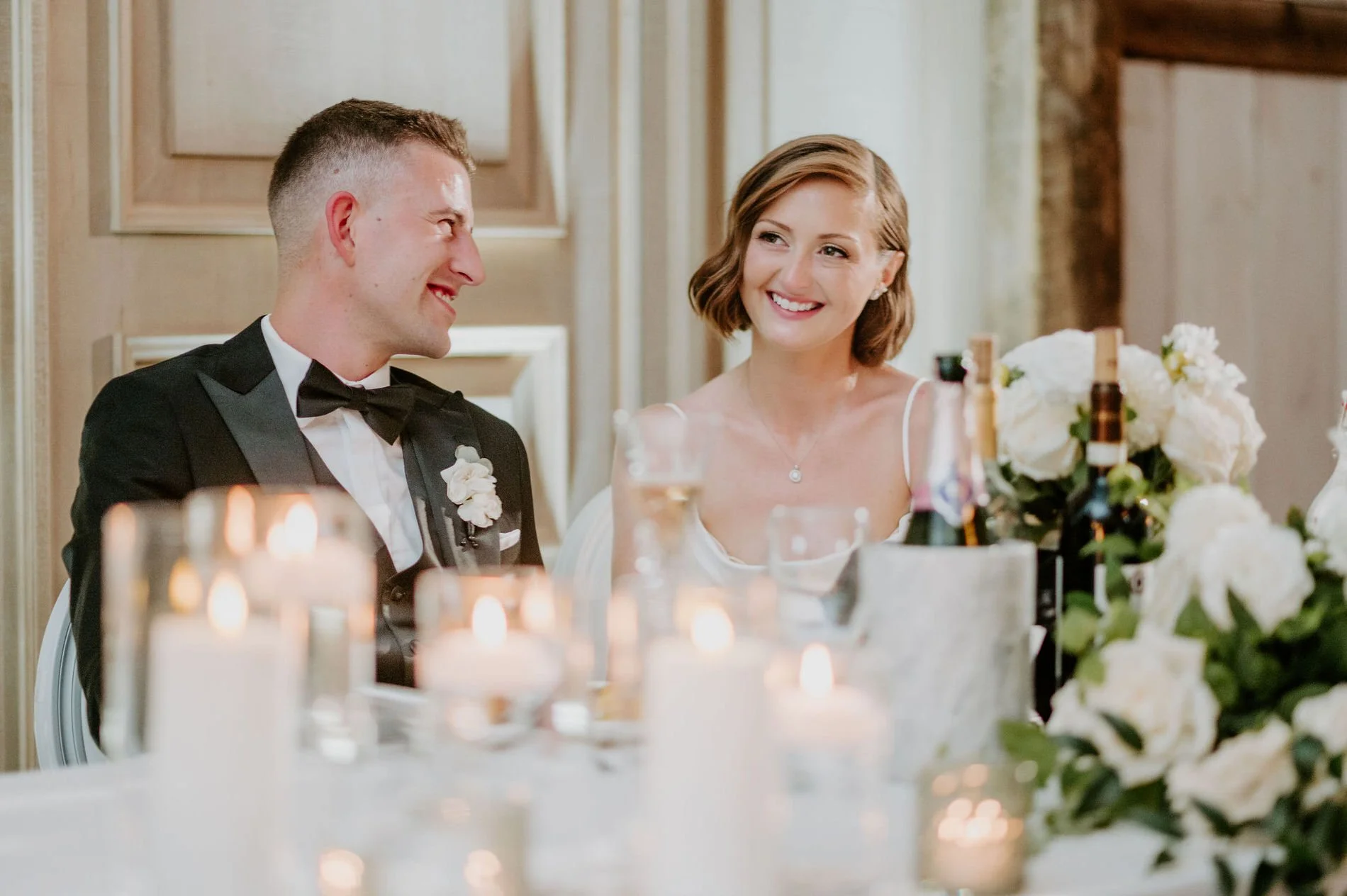 Emily and Austin exchanging smiles at the candlelit head table