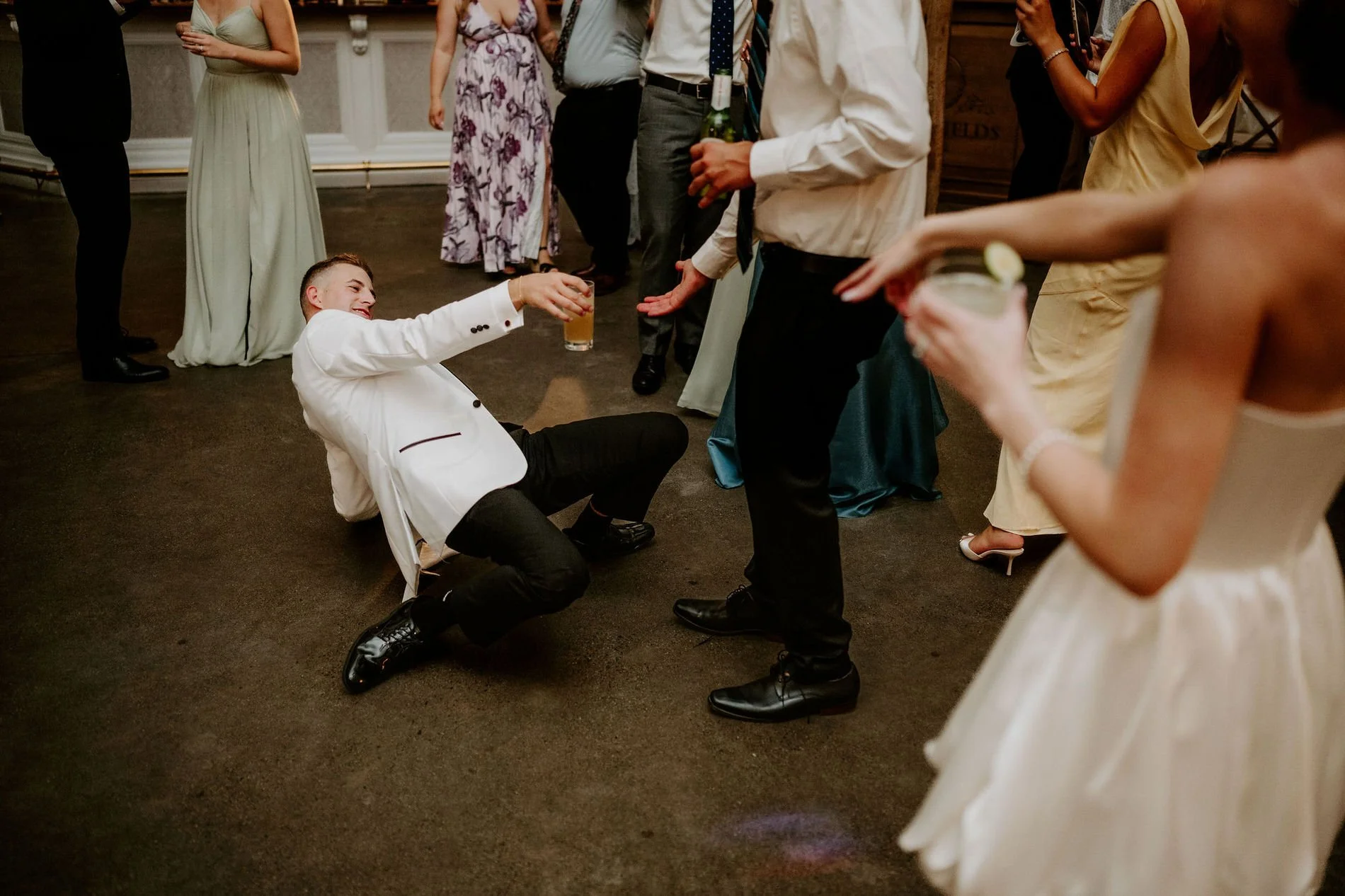 Austin in a white dinner jacket dropping to the floor mid-dance, drink in hand