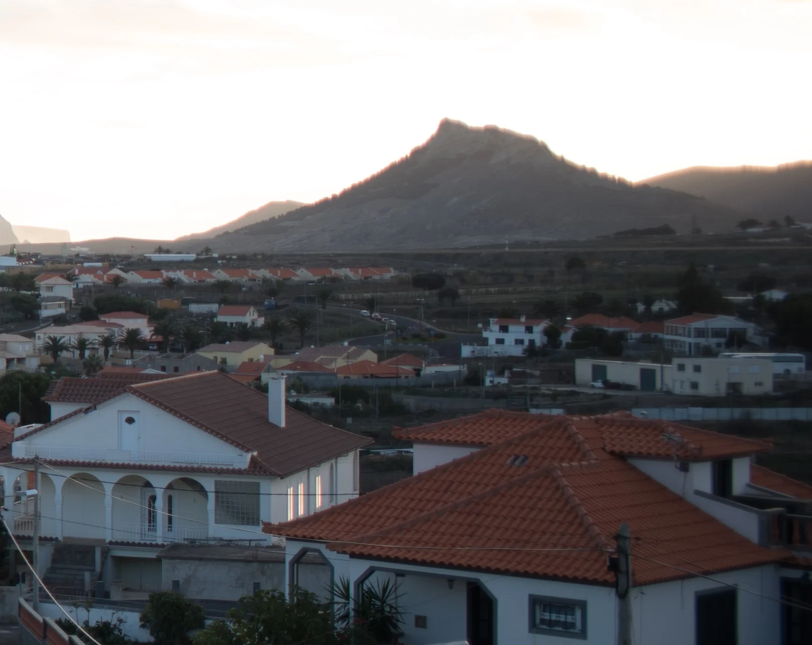 At maximum aperture, CA, softness and ghosting are quite visible in the mountains in the background. Also the houses on the right are smudged and lacking sharpness.