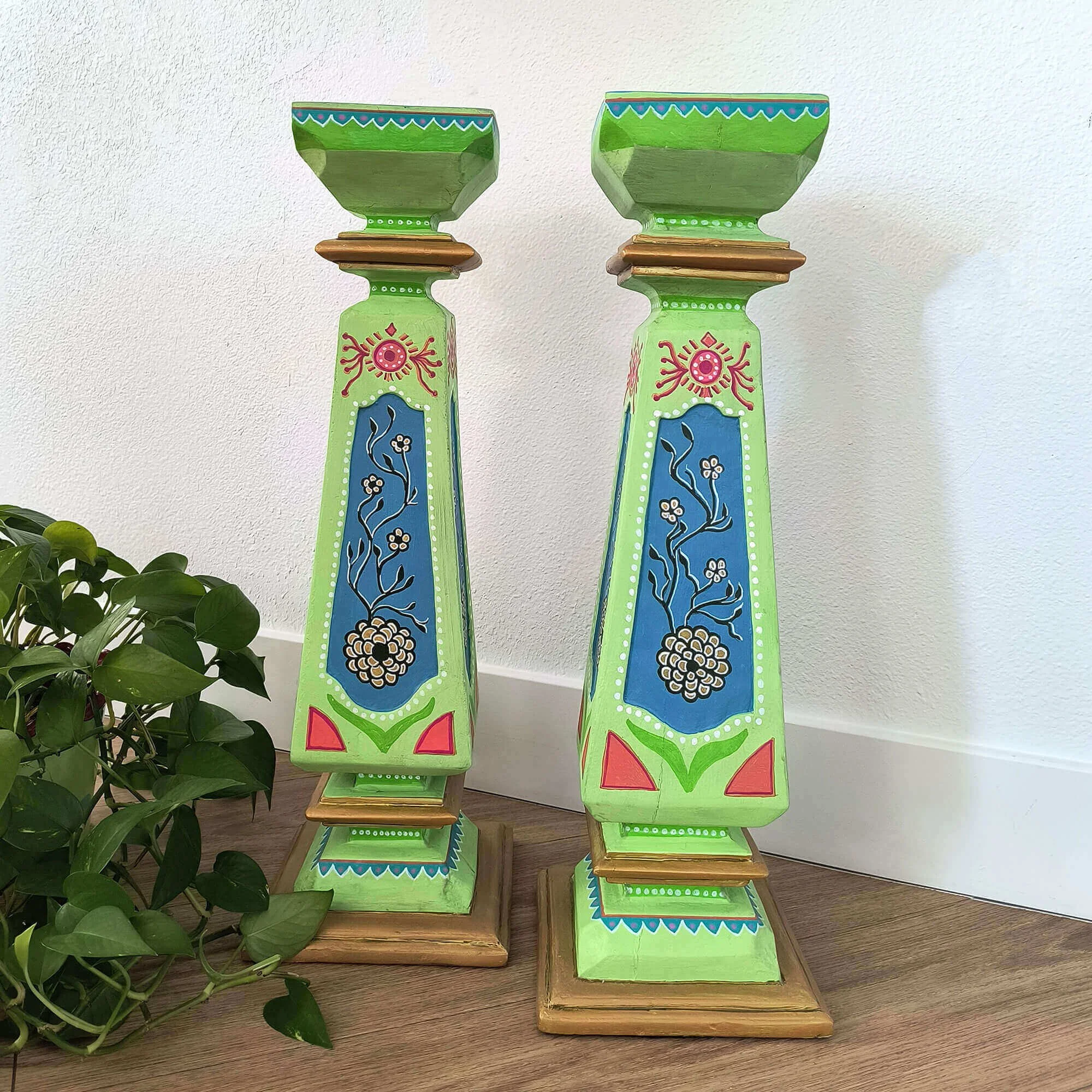 Hand-painted colorful decorative pedestals set in folk art furniture style with floral and sun motifs.